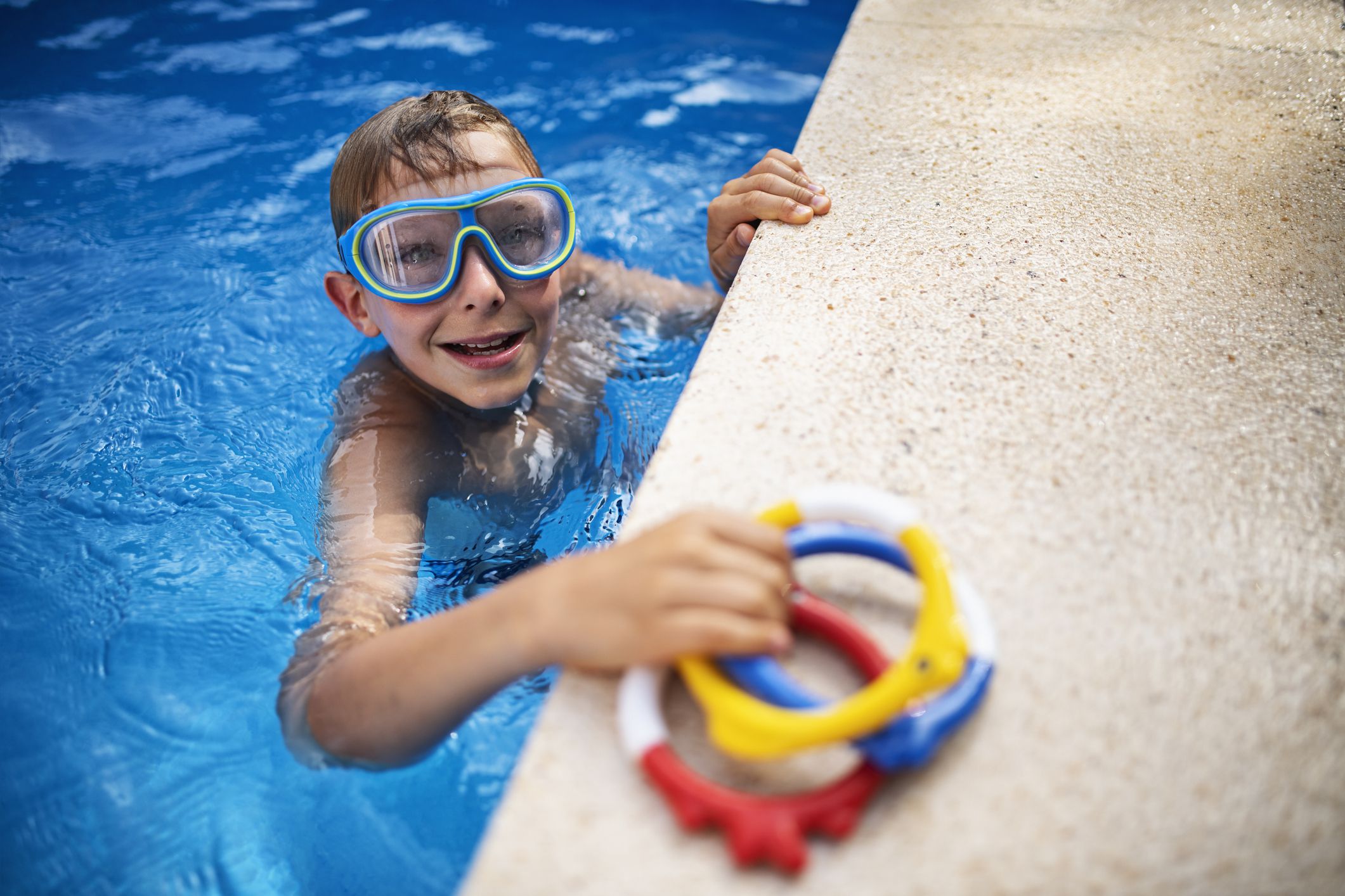 Little boy is diving in the swimming pool. The boy is holding toys that he retrieved from the bottom of the pool.Shot with Nikon D850