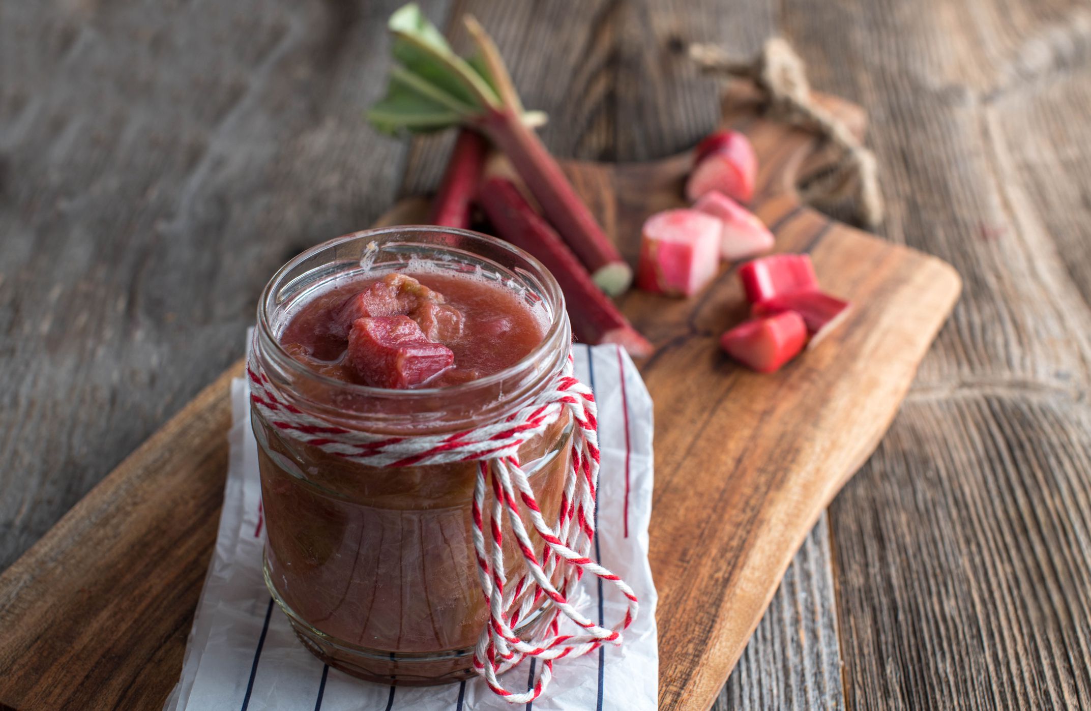 Fresh cooked rhubarb compote. Served in a jar on wooden table background with copy space