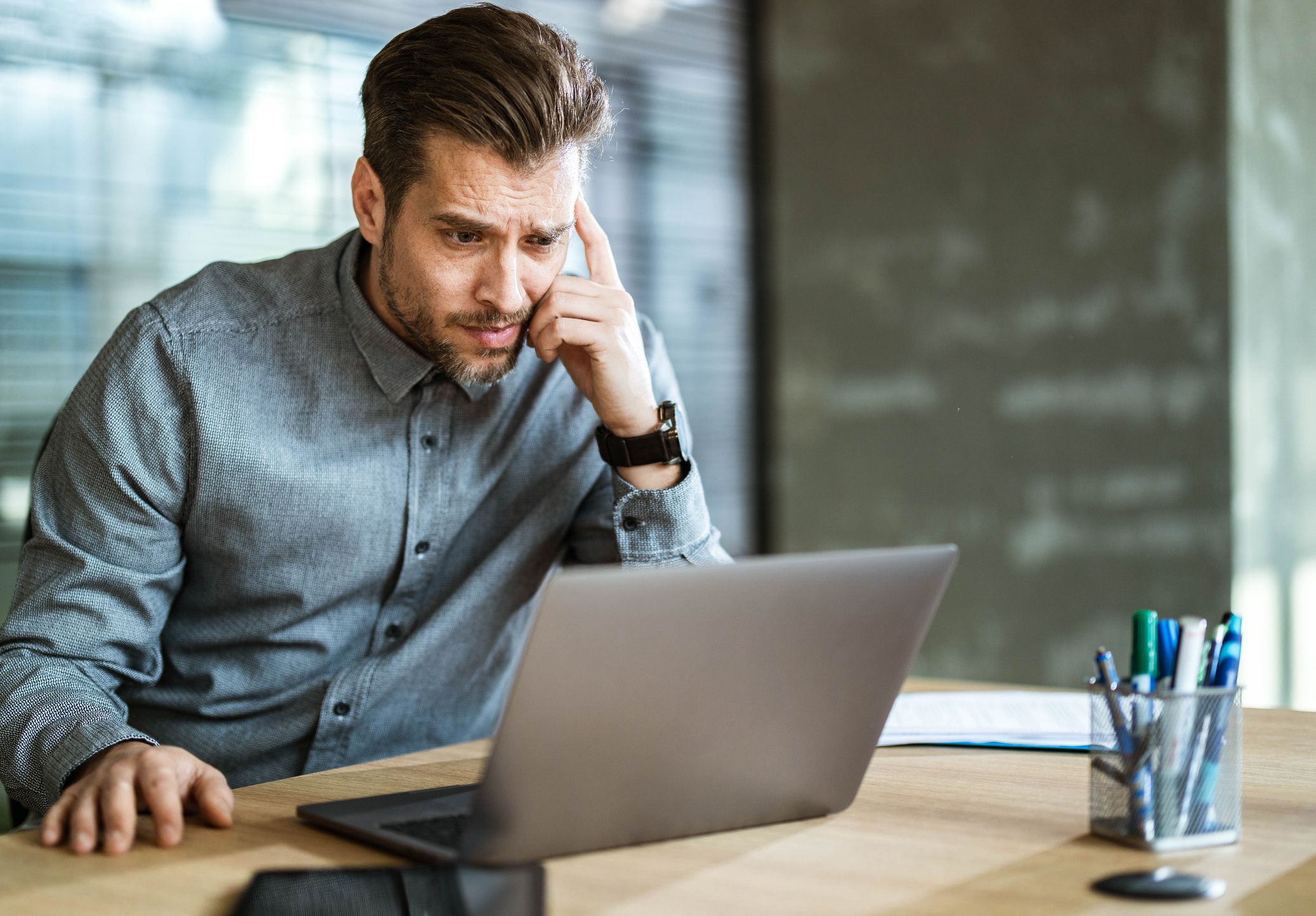 Displeased businessman having problems while surfing the Internet on a computer in the office. Copy space.