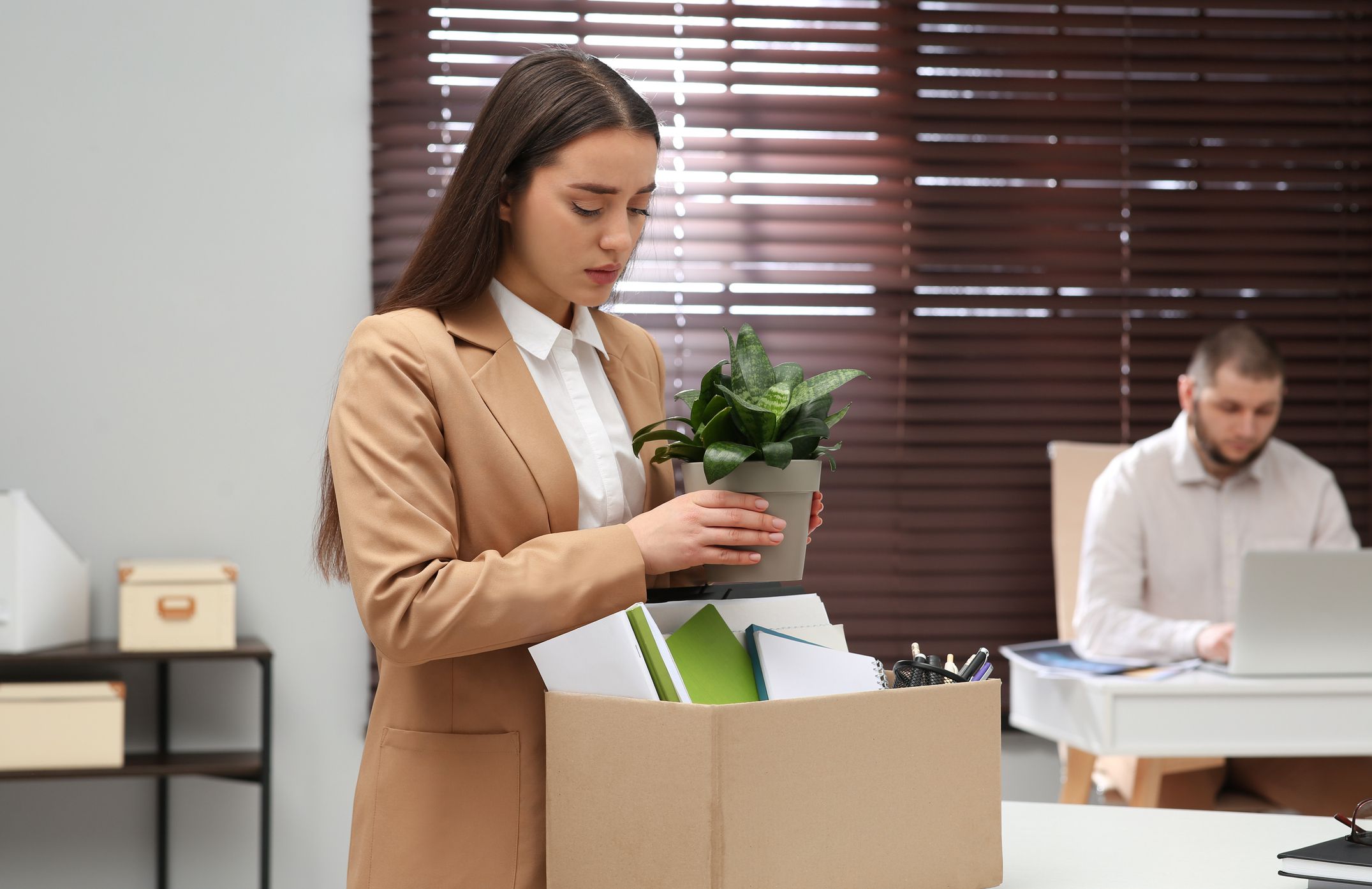 Dismissed woman packing personal stuff into box in office