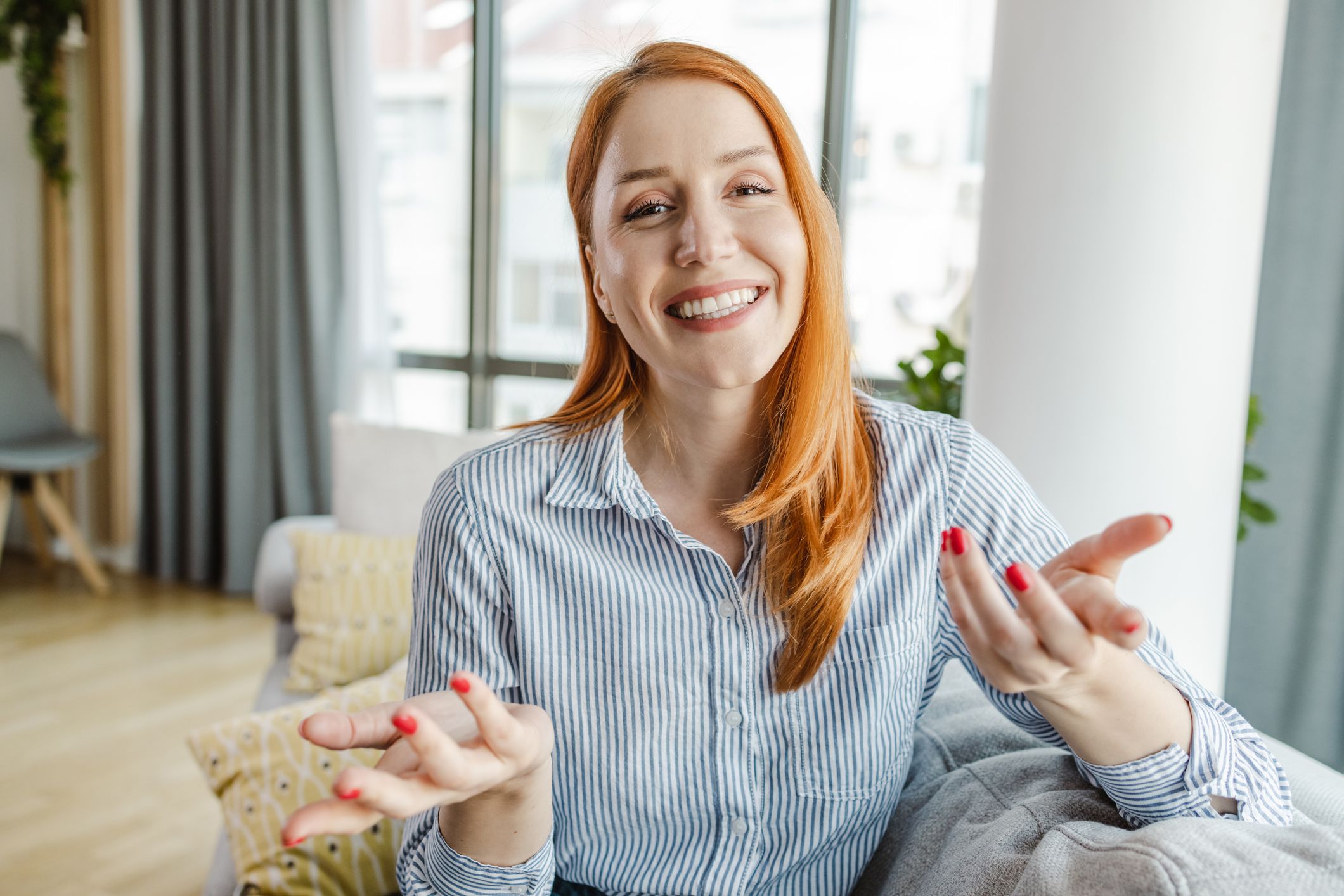Portrait of a young woman talking and gesturing with hands while looking at the camera