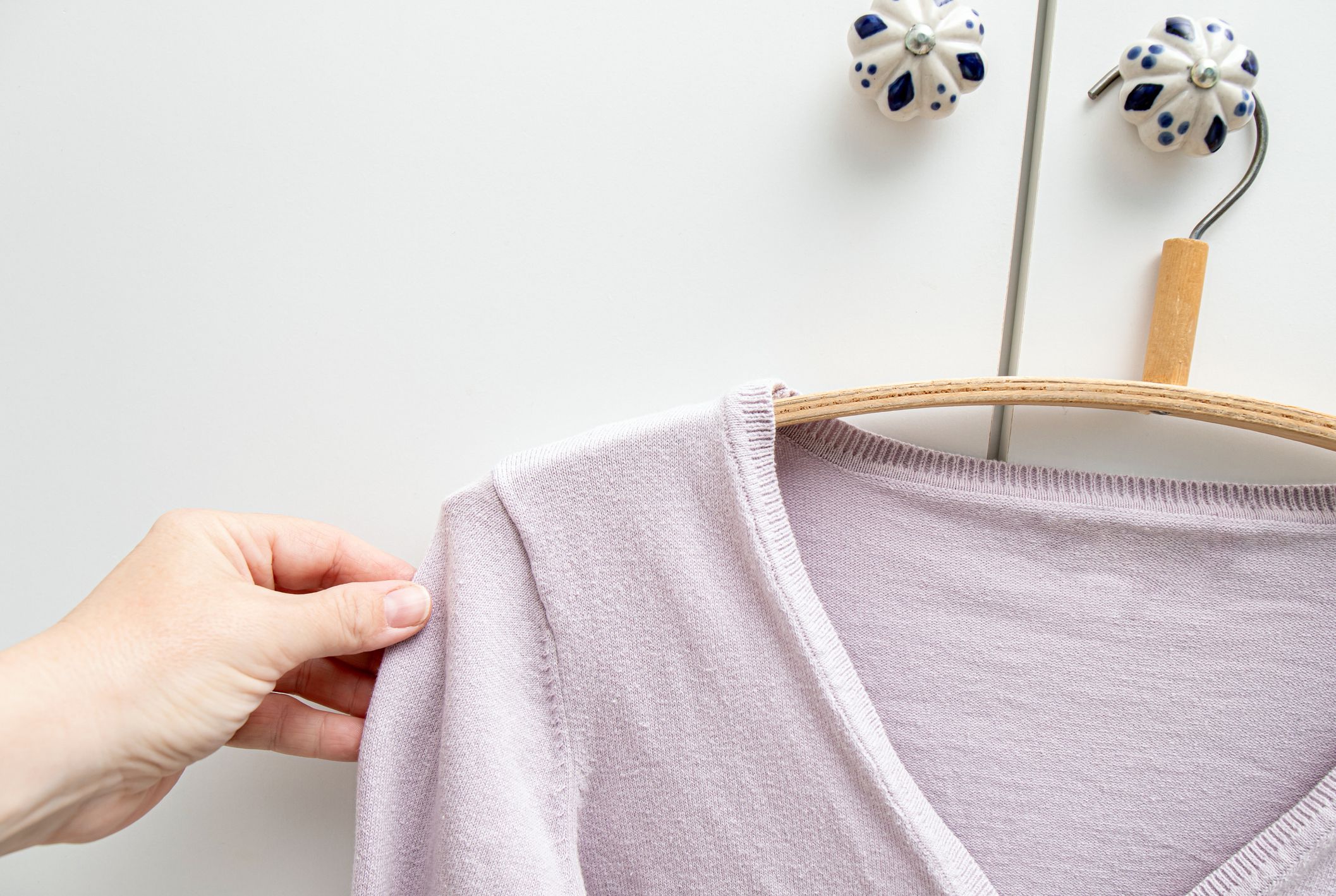 Stretched Out from shoulders cardigan hanging on bad shape hanger in home room. How to avoid fabric stretch marks concept.