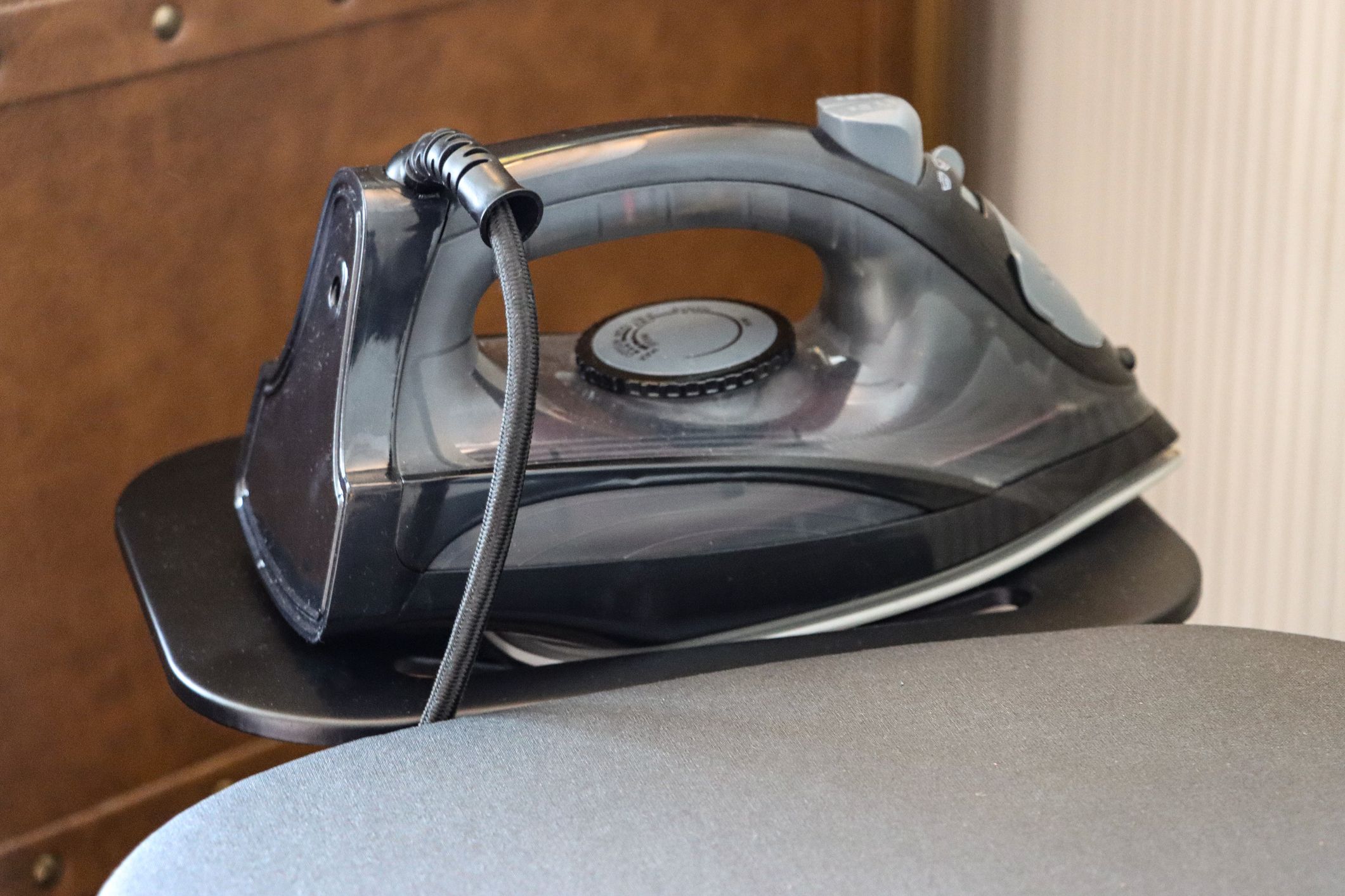 Stock photo showing silver ironing board cover on board with iron sitting in the ironing board tray.