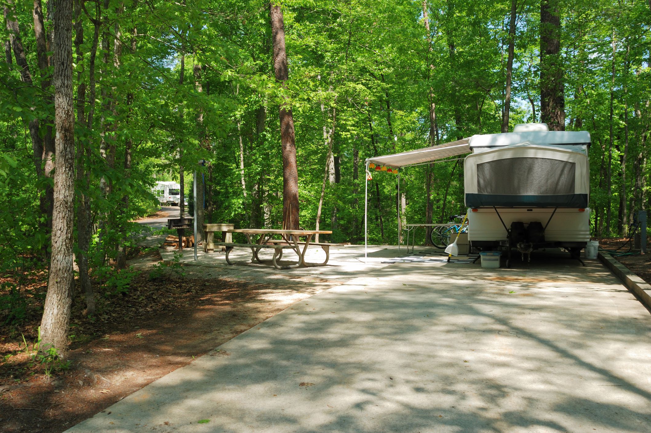 camper in woodsy shade with awning