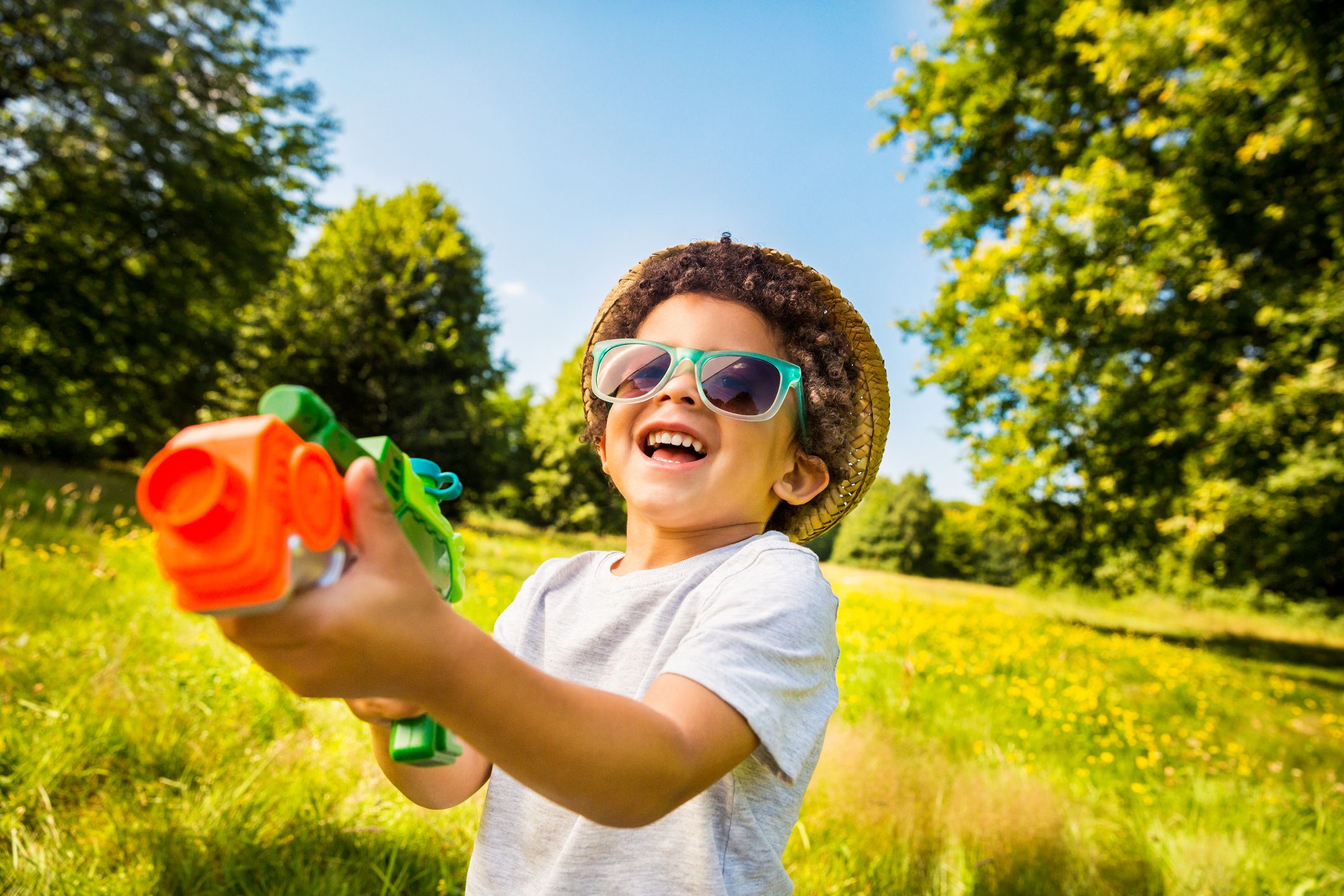 Fisheye portrait of little boy shooting water with squirt gun