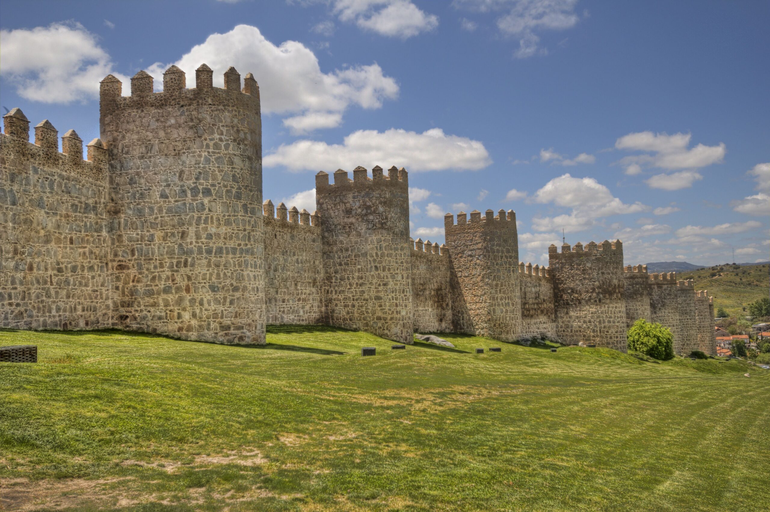 Ancient city walls and grass lawn in the old city of Avila, Spain