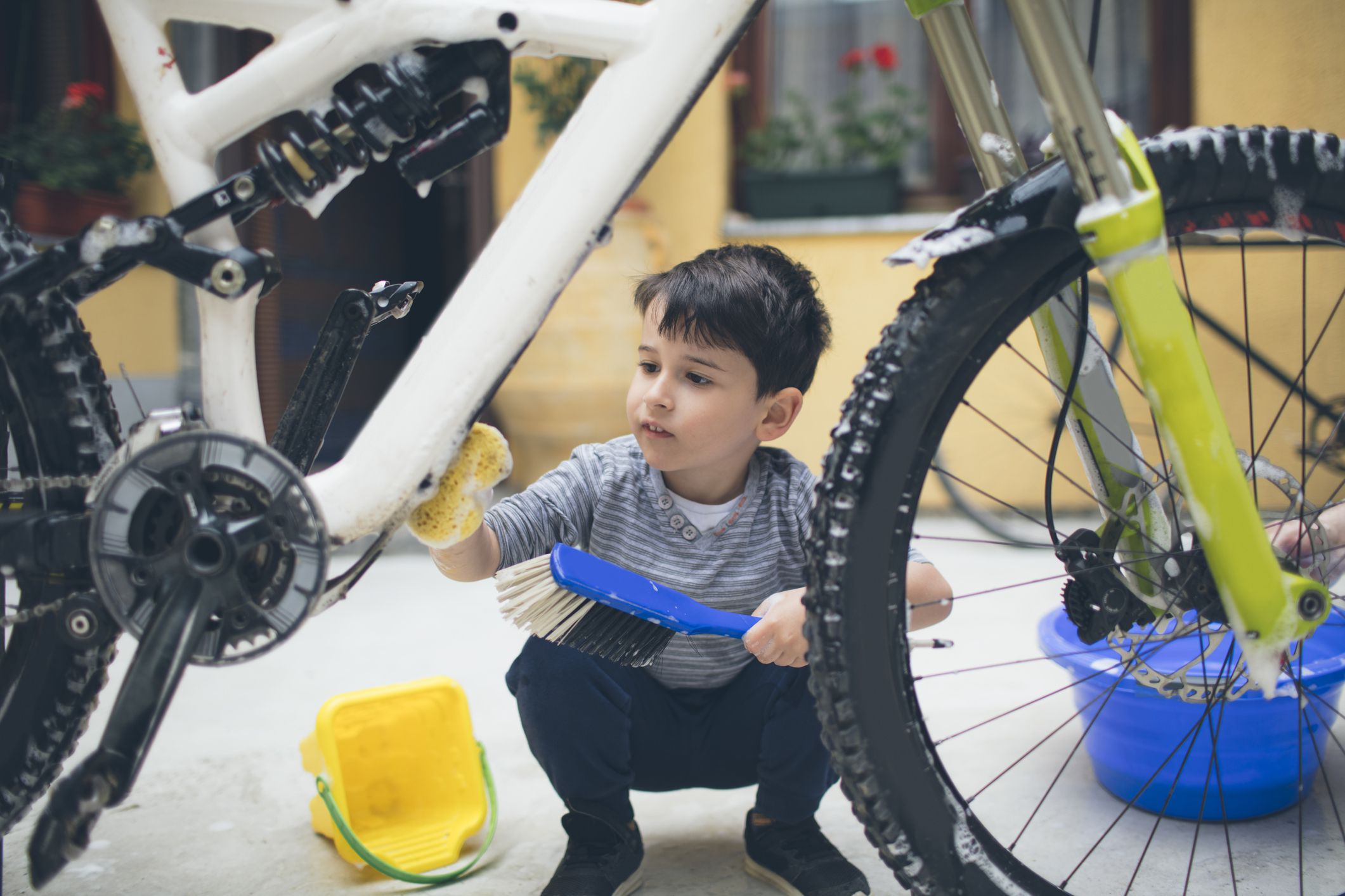 Little boy cleaning bicycle in his backyard.