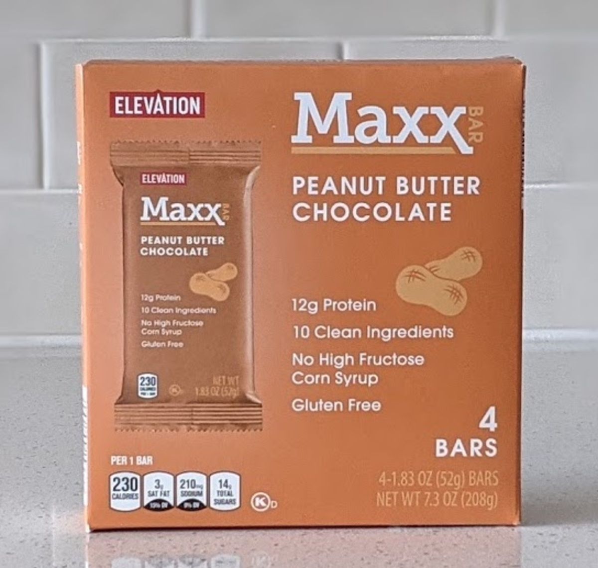 Box of Elevation Maxx Bar, Peanut Butter Chocolate, on a light grey countertop with light grey tiles in the background