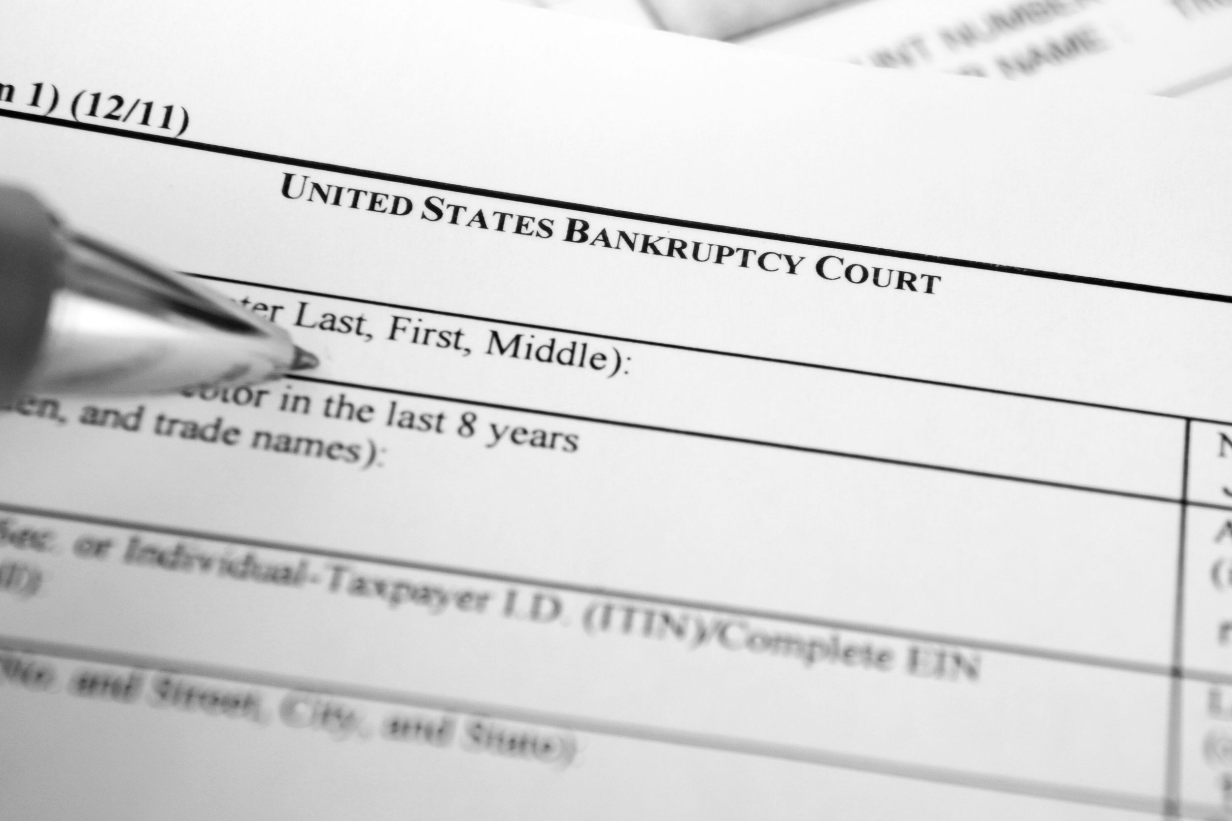 Closeup of a U.S. Bankruptcy filing form with pen on name area, selective focus of pen