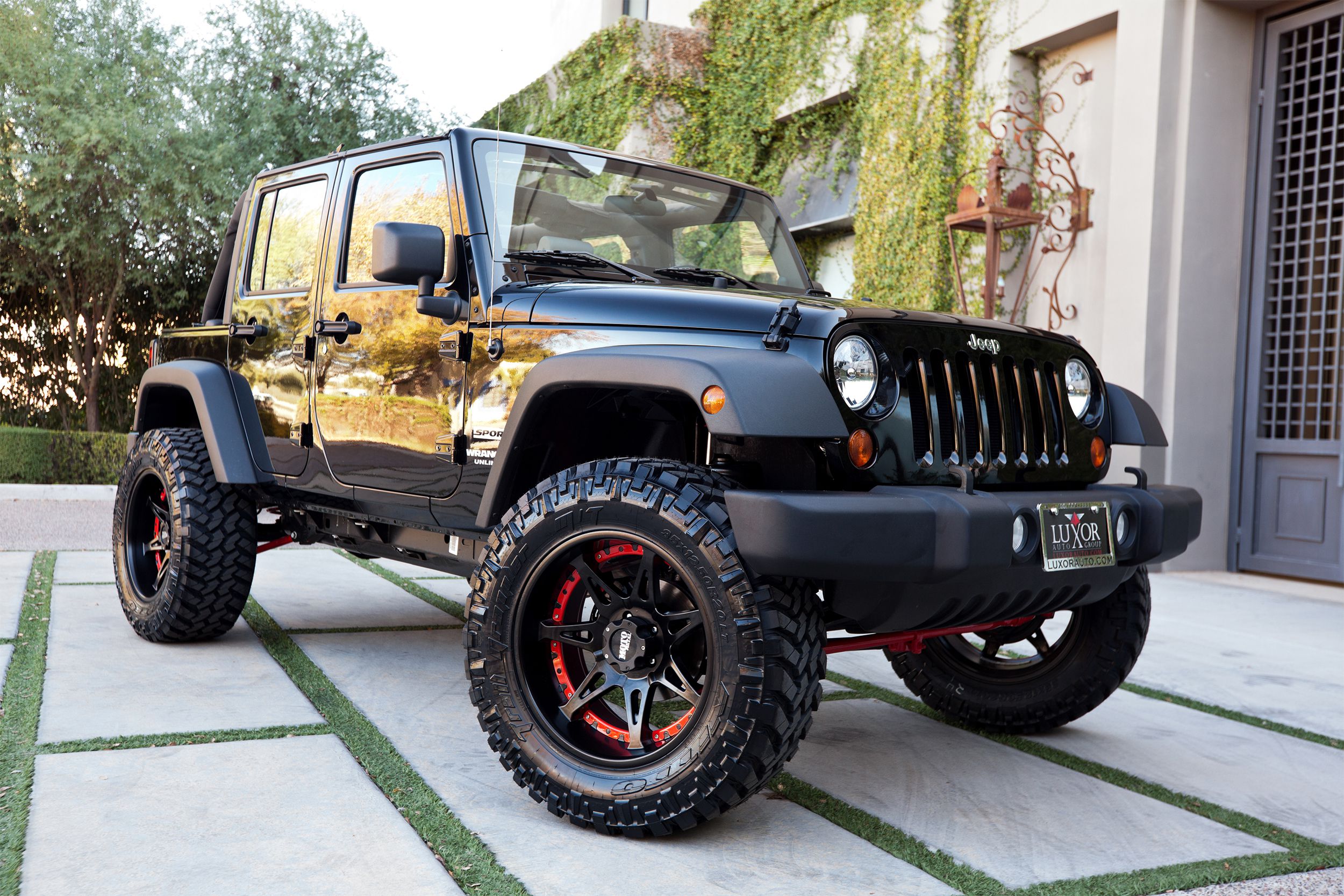 Clean black Jeep Wrangler in a drive bar in front of nice stone house.