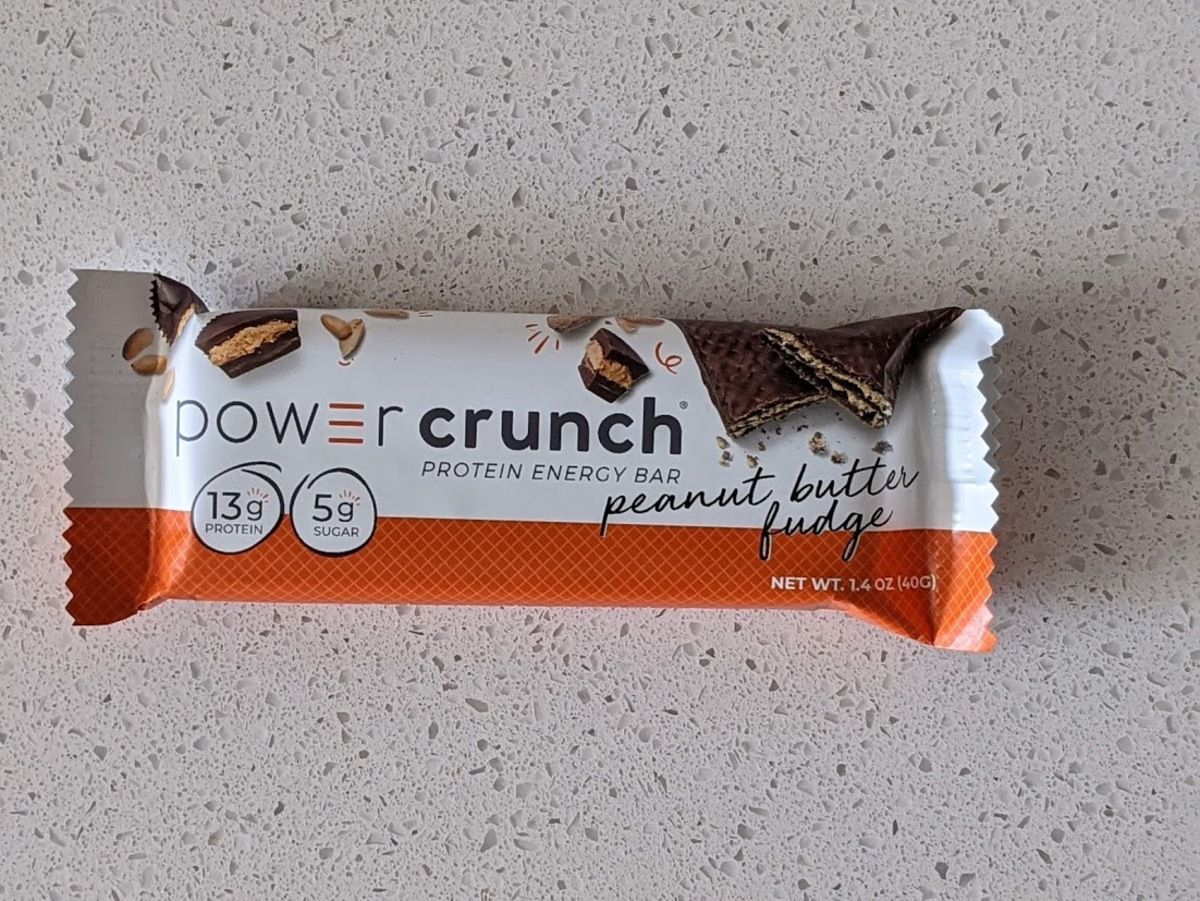 Power Crunch Energy Bar, Peanut Butter Fudge, on a light grey countertop with light grey tiles in the background