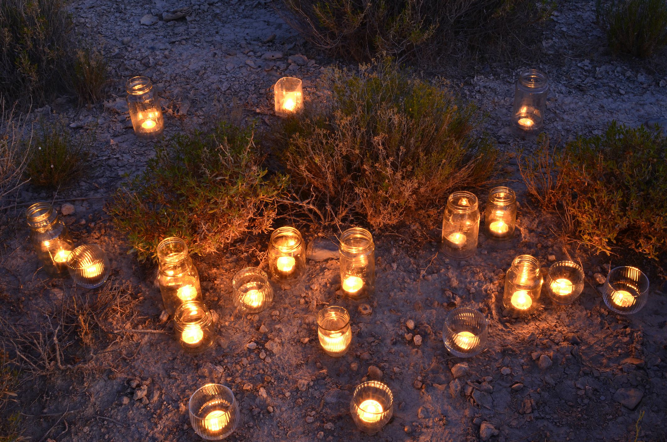 garden lantern night light candles illuminating upcycled glass jars outdoors in desert dirt amid desert plants in Mojave Desert, Pahrump, Nevada, USA