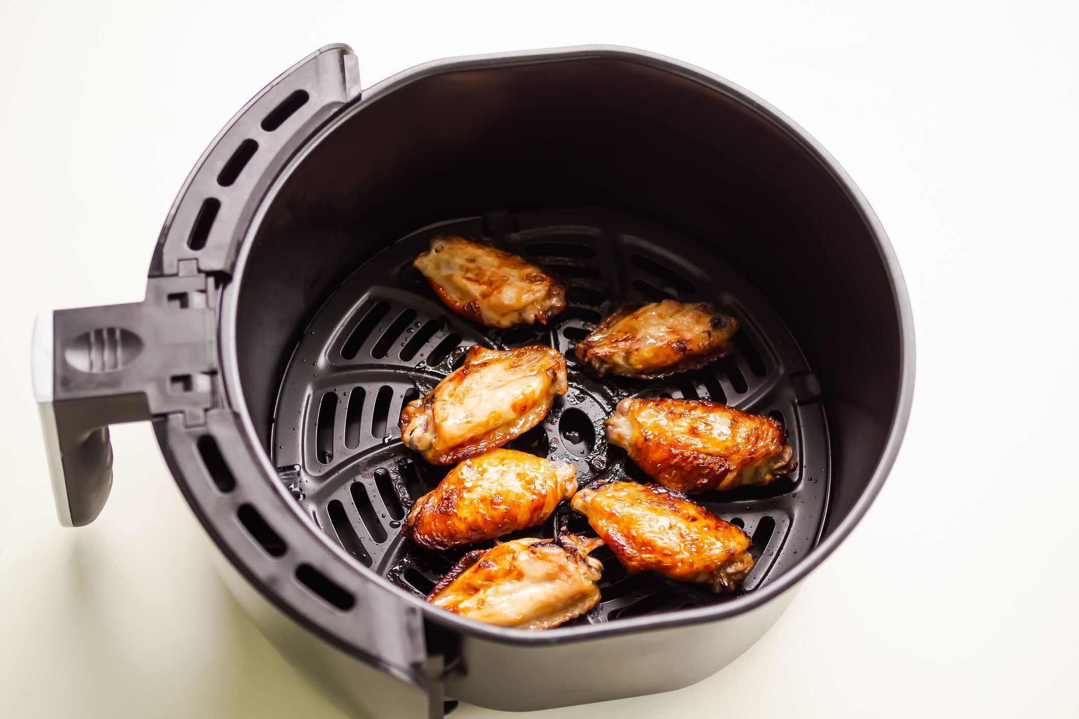 Baked chicken wings in Air Fryer on white table background. cooking for low fat control weight. food for health concept.