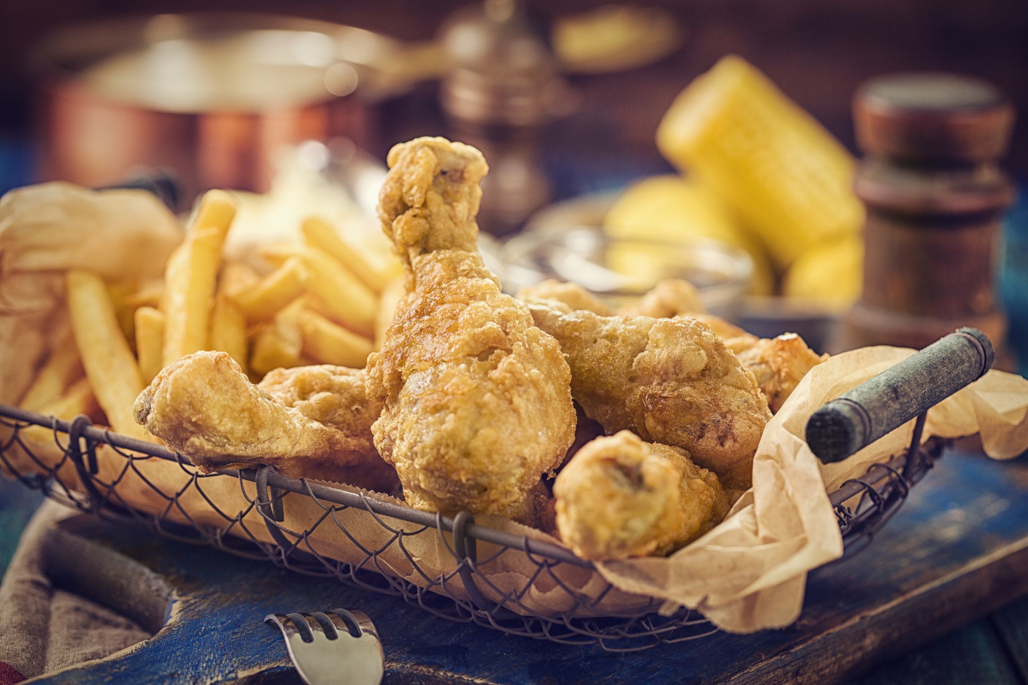 Homemade golden fried chicken legs witch french fries in a basket. Super crunchy and ready to eat.