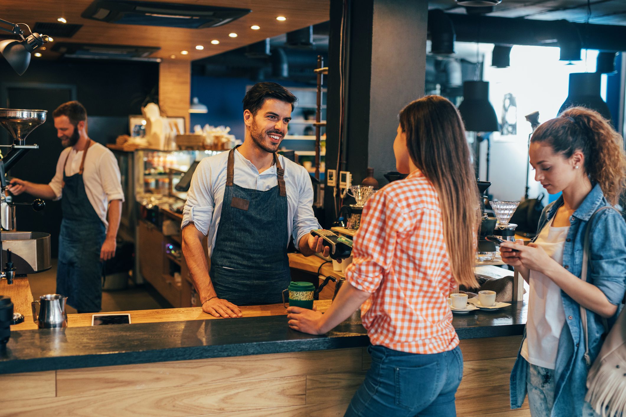 Customer making a contactless payment via credit card at a cafeteria.
