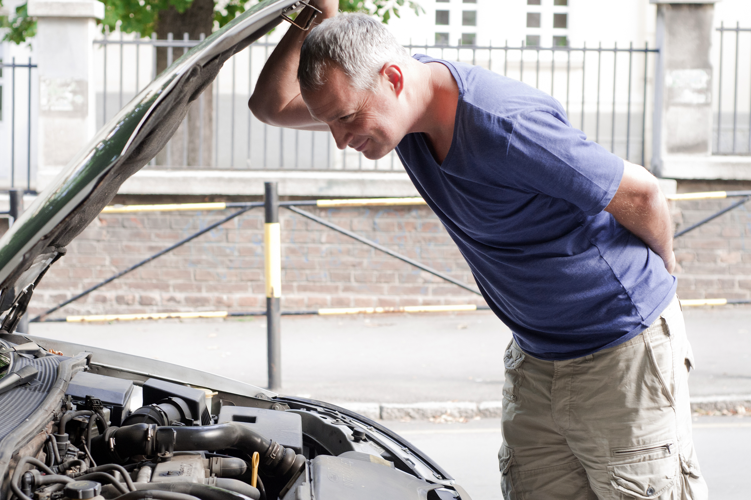 man looking under the hood of his car