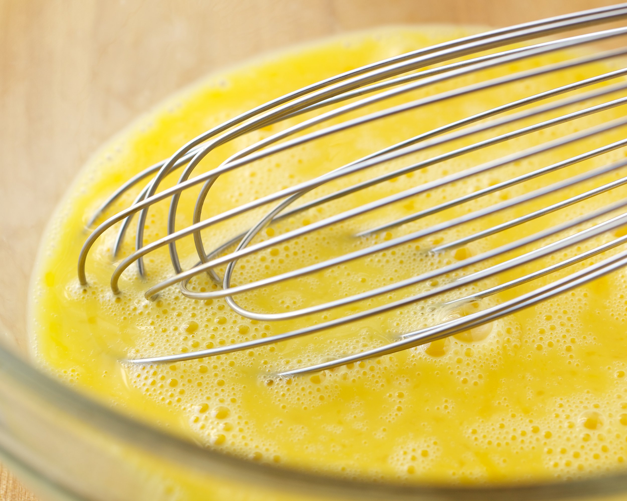raw eggs and whisk in glass bowl