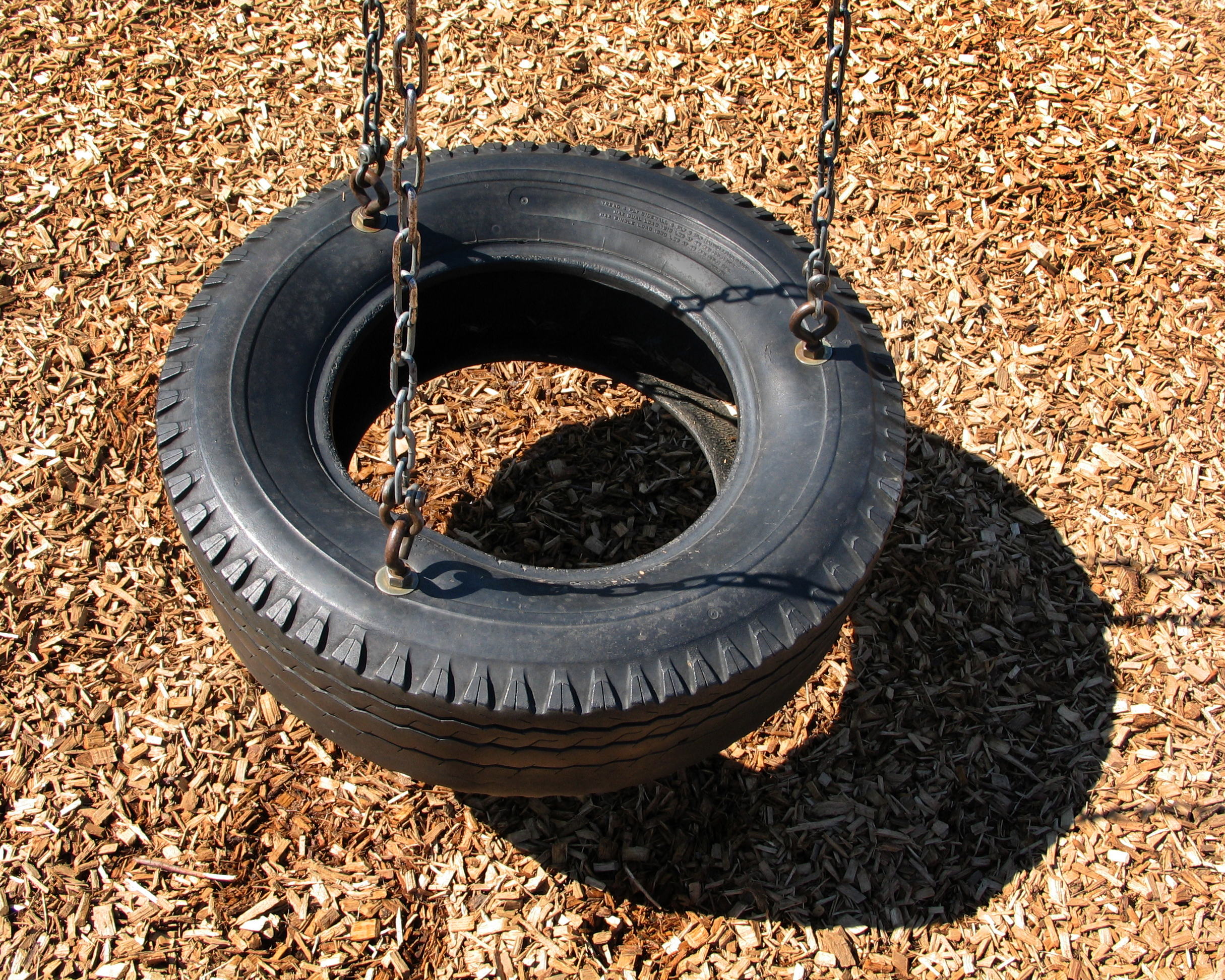 A tire swing, as seen from above looking down, on a bed of mulch