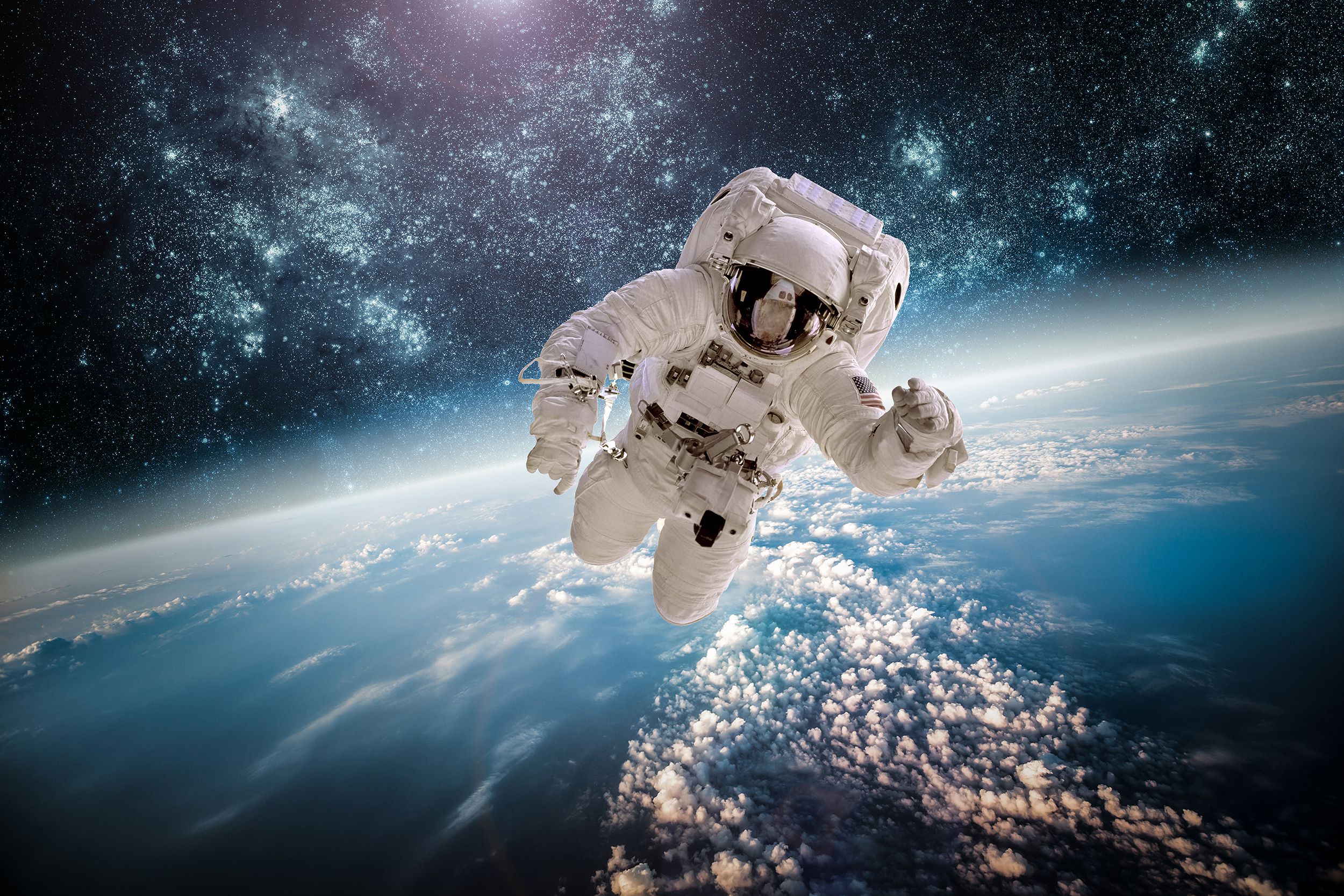 Astronaut floating in low earth orbit, facing the camera in full space gear with Earth and outer space in the background