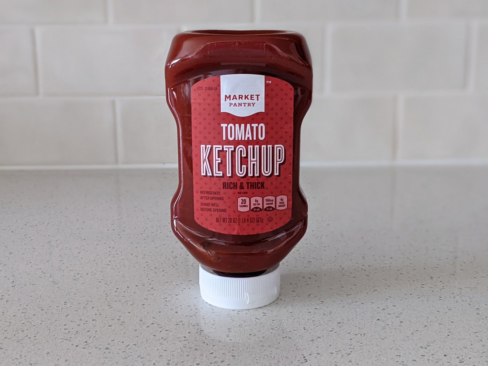 A bottle of Market Pantry Rich & Thick Ketchup on a speckled ivory kitchen countertop, light beige tile wall in the background