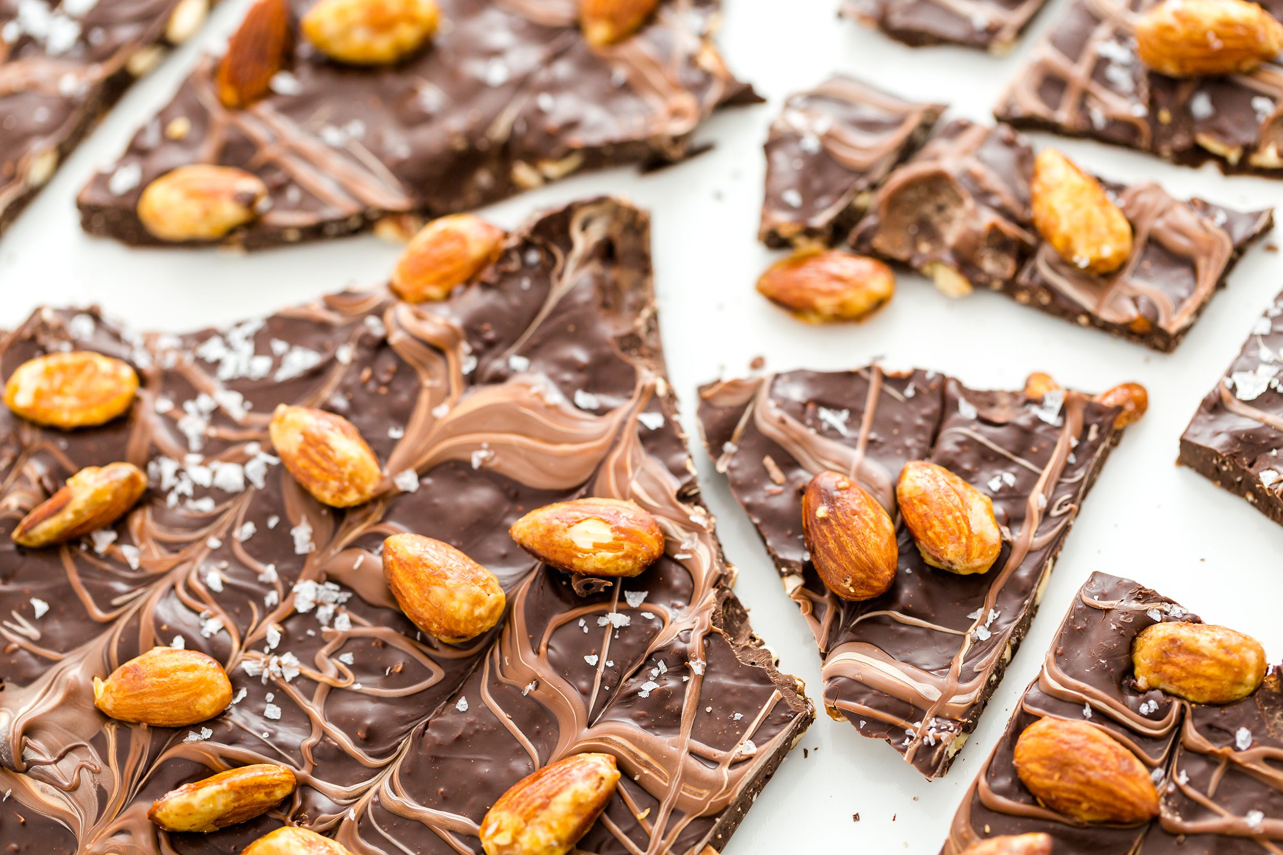 Closeup of chocolate with almonds bark cut in many large pieces on a white background