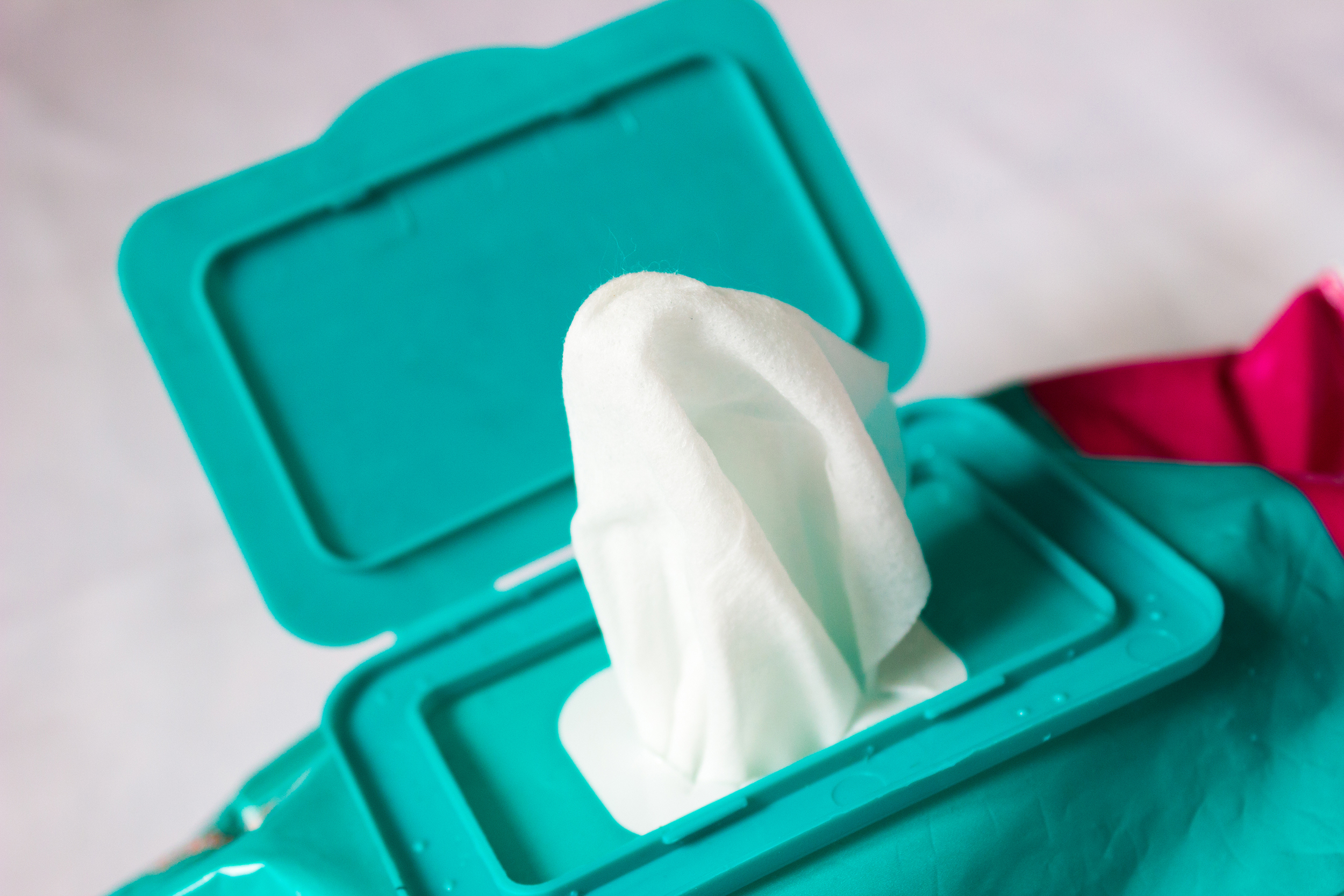 Closeup of a disposable wet wipe out of package, aqua wipe dispenser, selective focus, blurred grey background