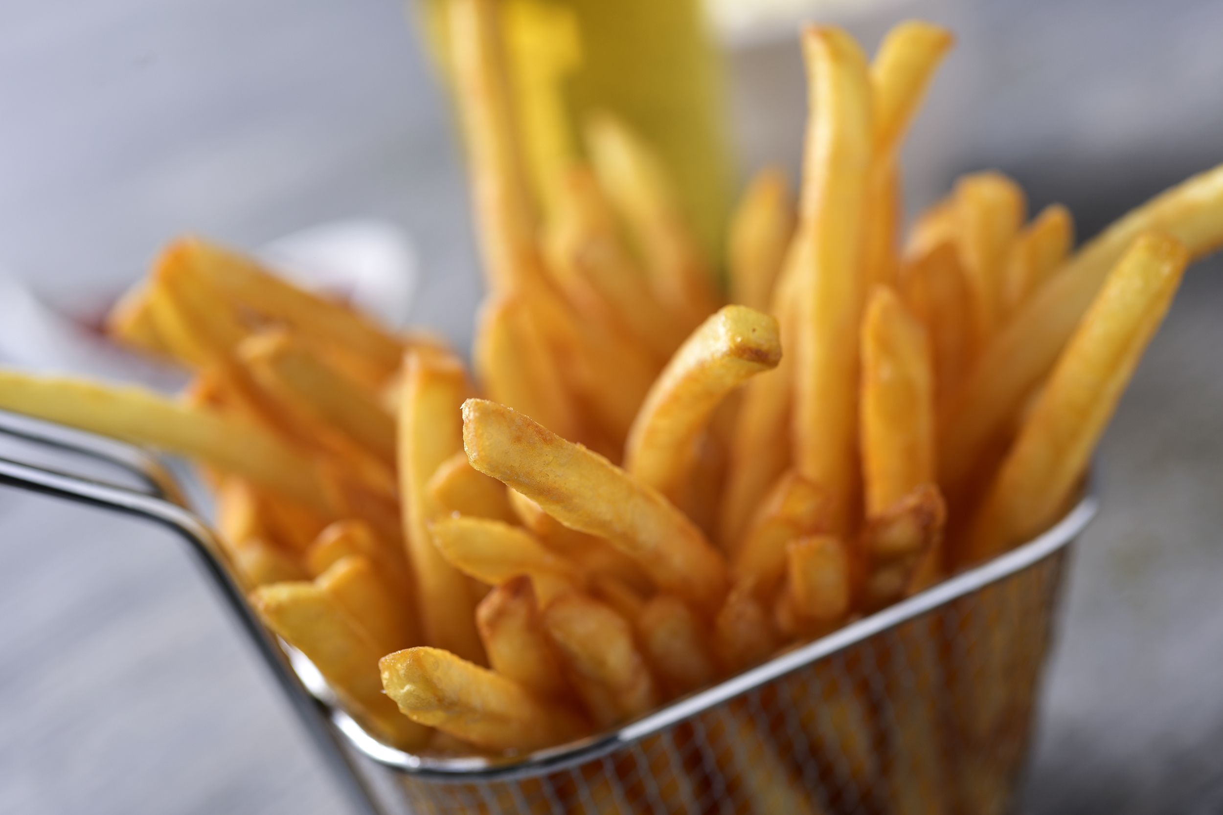 Fresh French fries in a metal basket