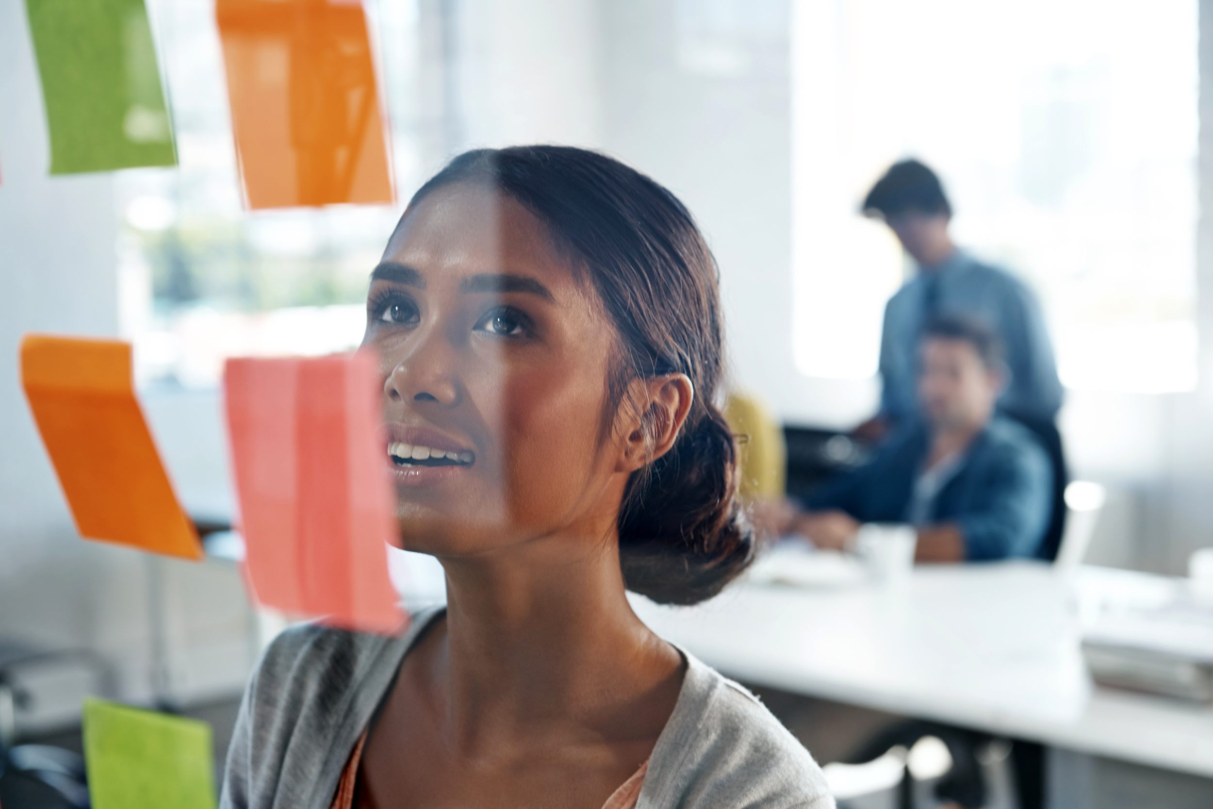 Employee looking at post-it notes on the office wall