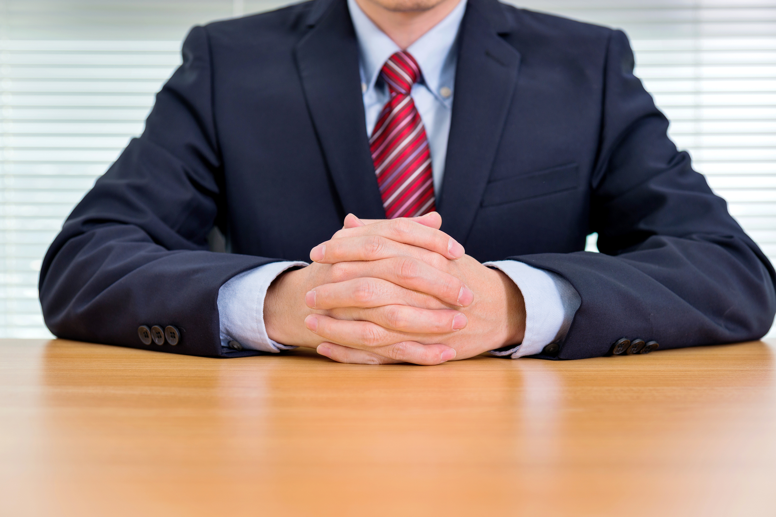 Boss at desk with hands folded