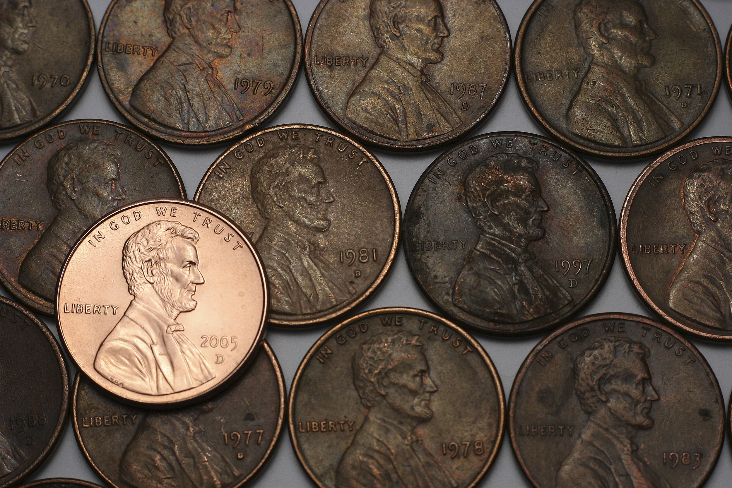 A new shiny 2005 U.S. penny on top of a background of older dull U.S. pennies, showing a grey background along the edges