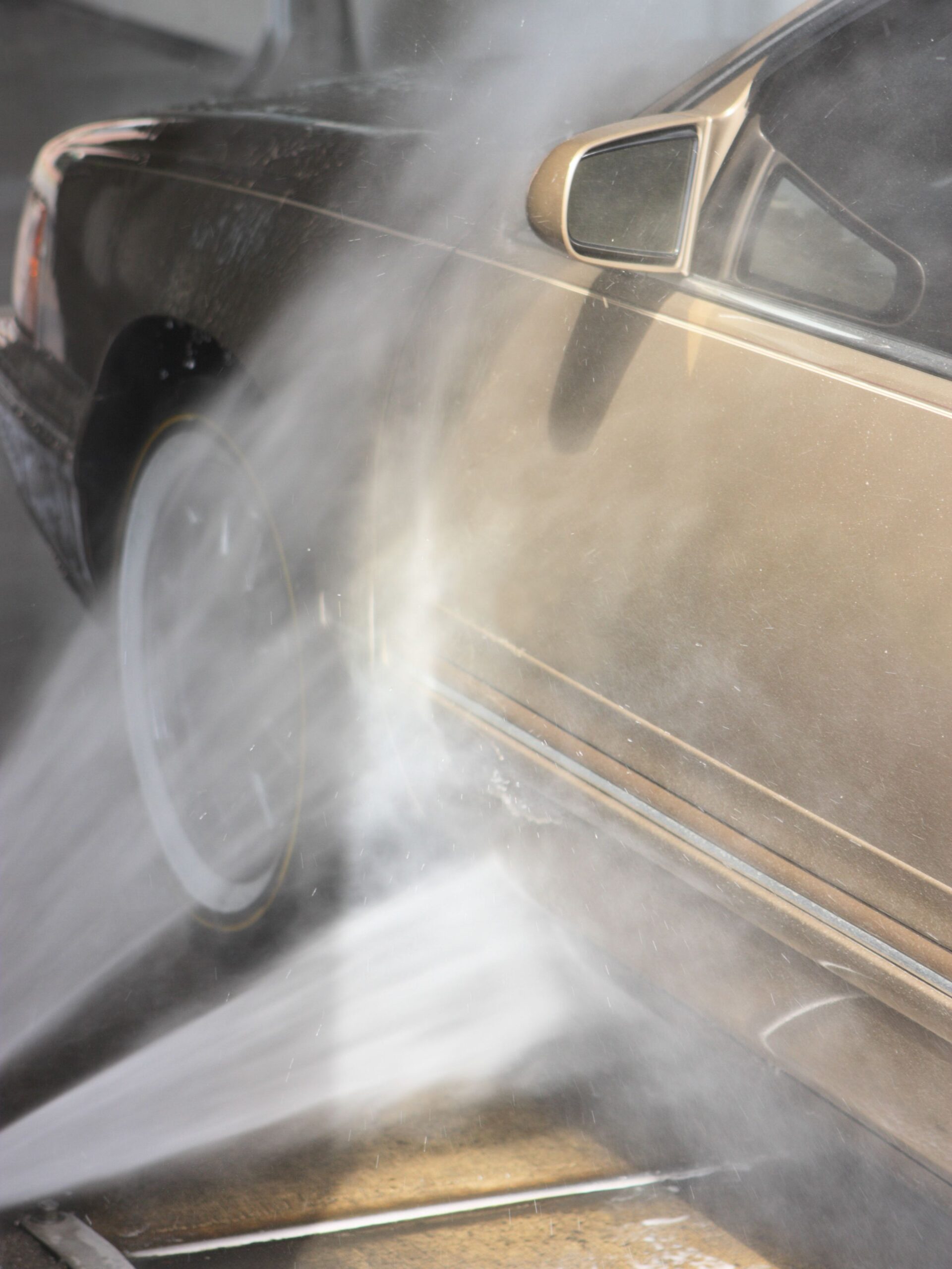 Power car wash soap spray water cleans gold door panel with interesting lighting.