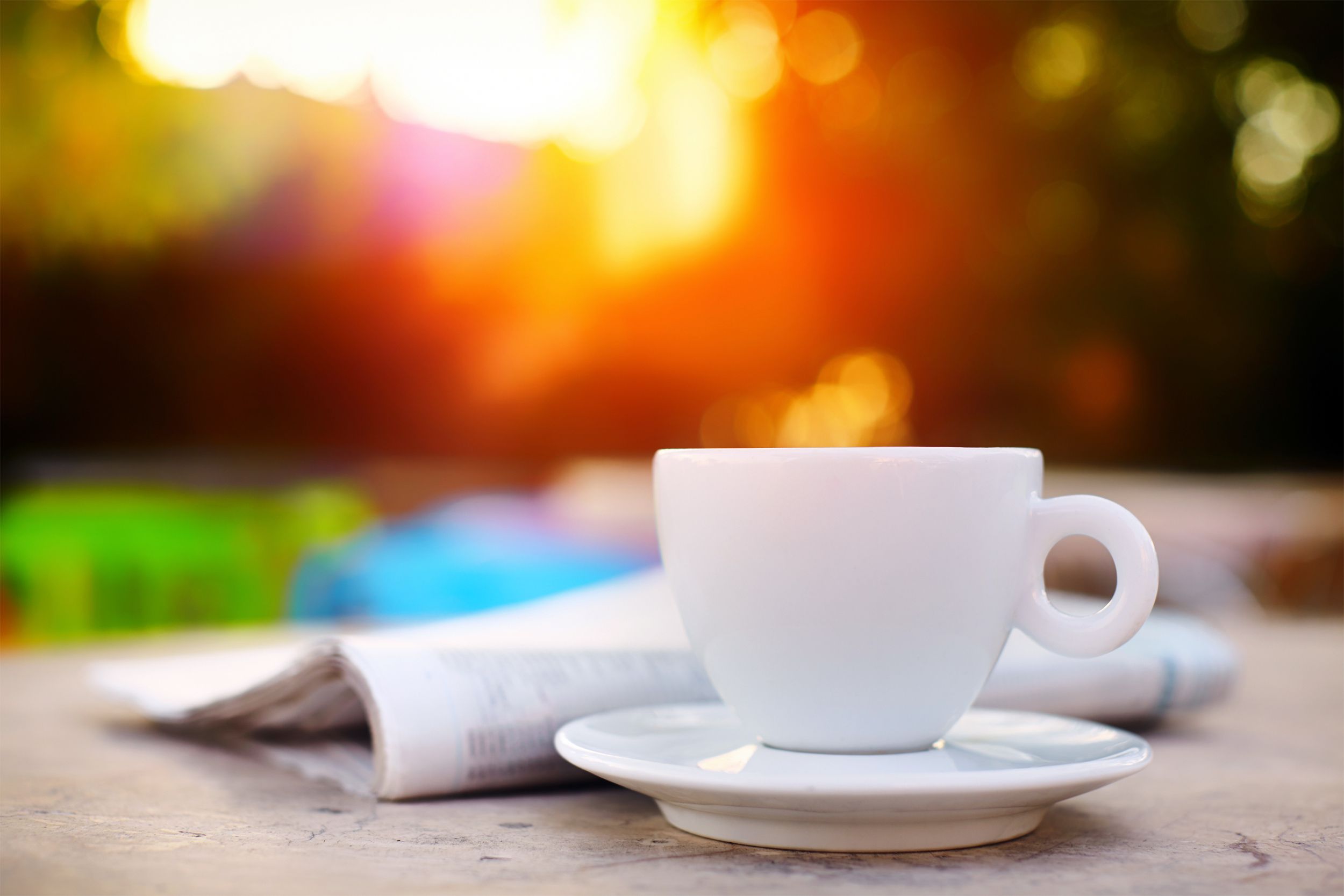 Cup of coffee or tea next to a newspaper outside