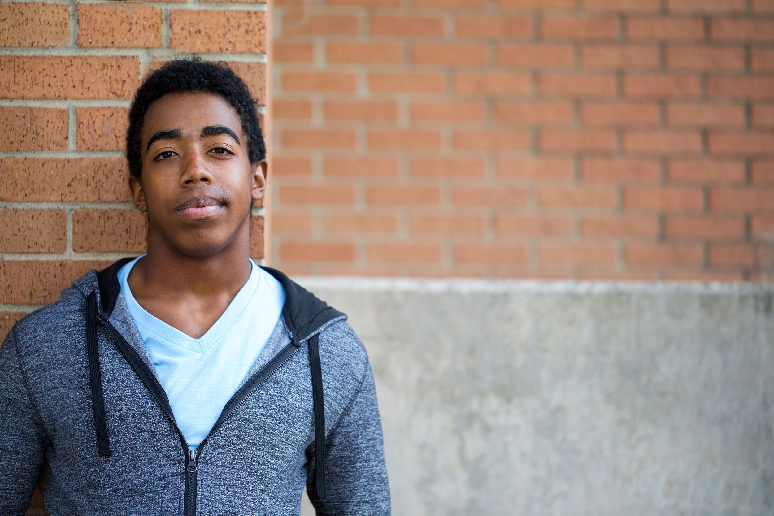 High school student standing against a brick wall