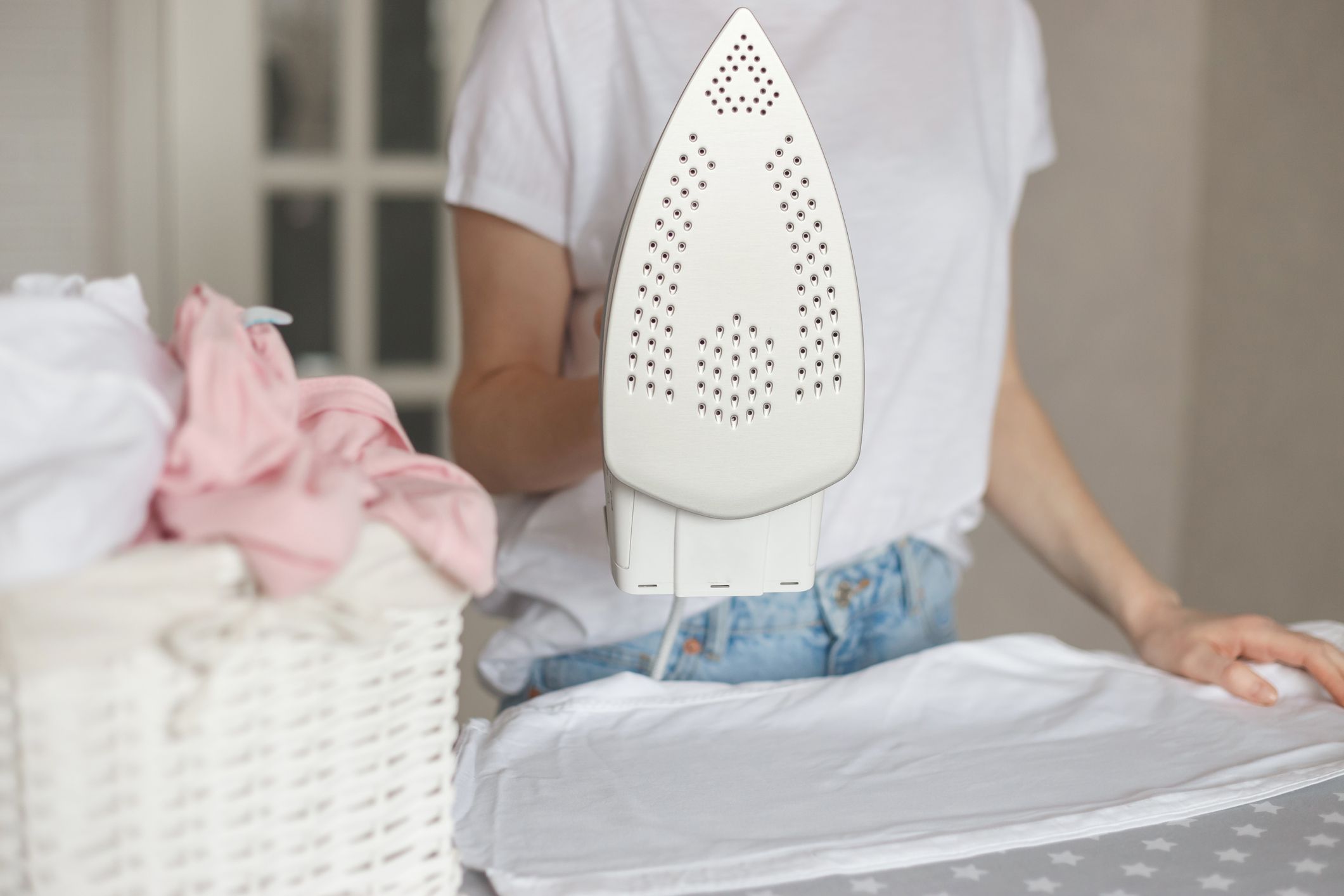 Woman holds modern styled iron with non-stick cover while ironing.