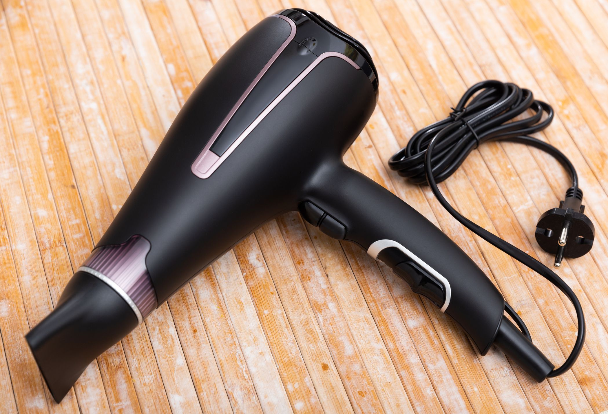 Photo of black blow dryer over wooden surface.