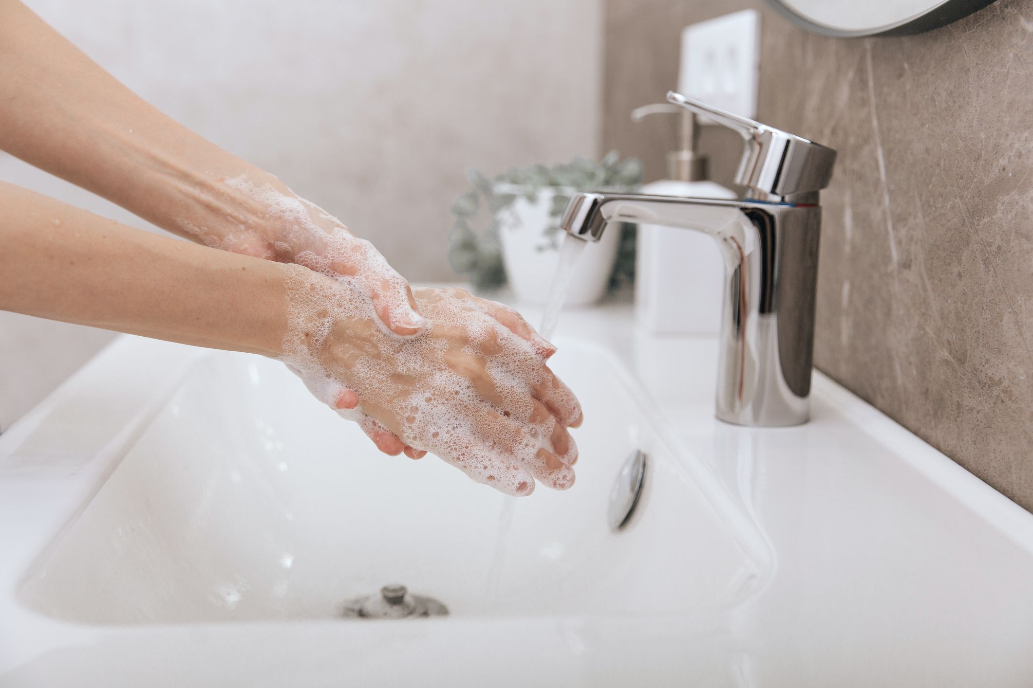 Washing hands under the flowing water tap. Hygiene concept hand detail. Washing hands rubbing with soap for corona virus prevention, hygiene to stop spreading corona virus in or public wash room.