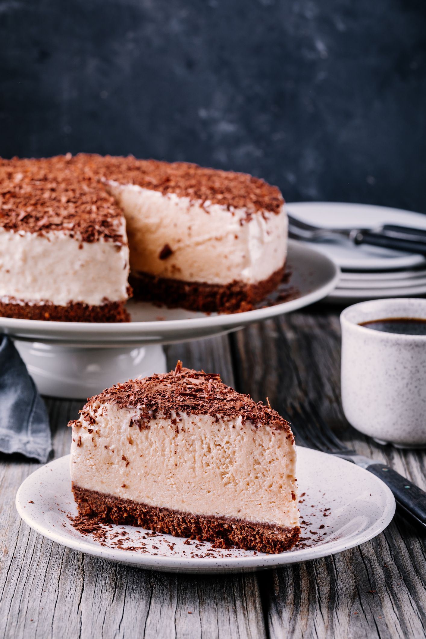 A piece of cold chocolate cheesecake on a plate on wooden rustic background