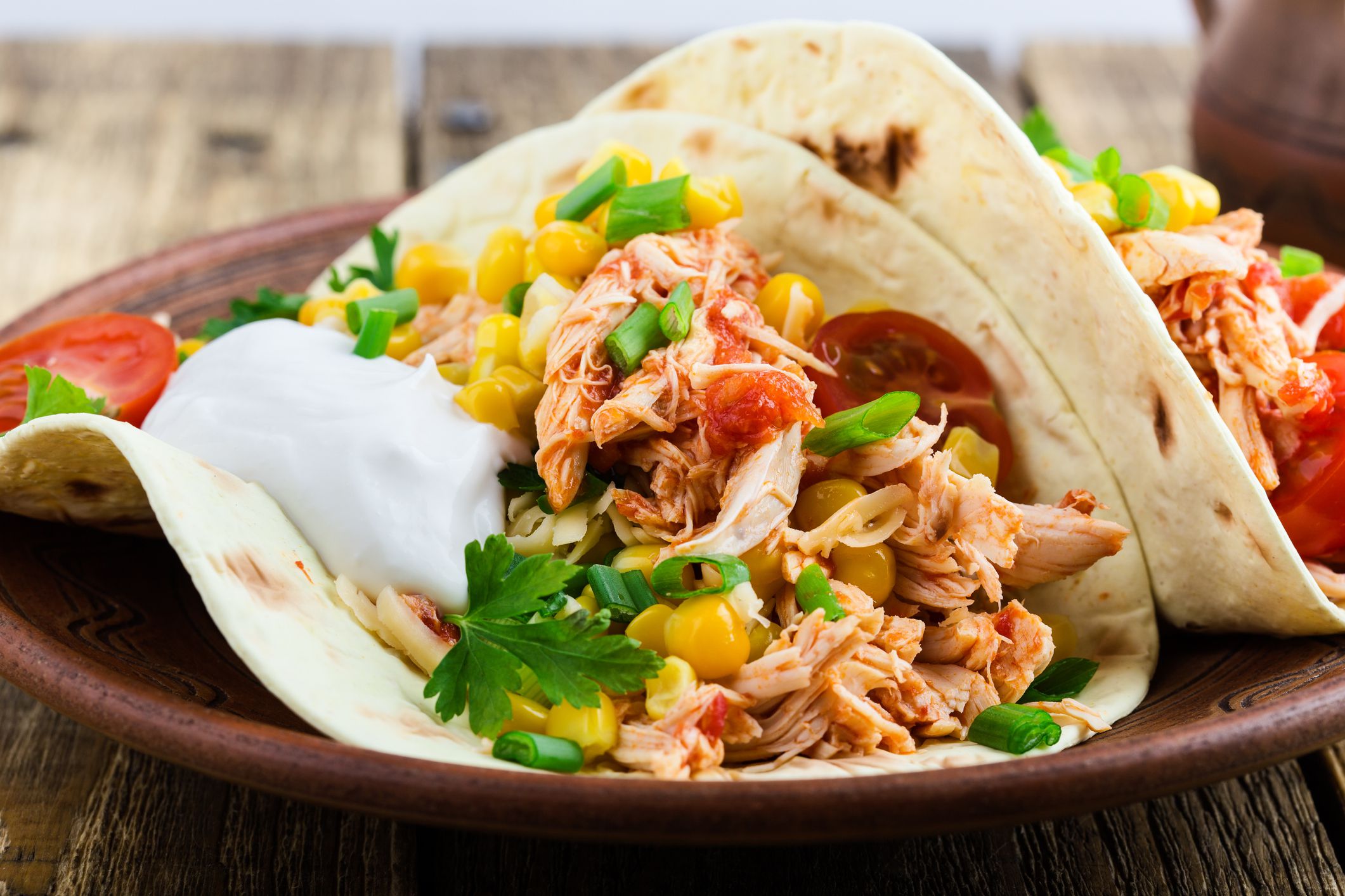 Homemade slow cooker chicken taco with corn served on rustic ceramic plate on wooden table, mexican style