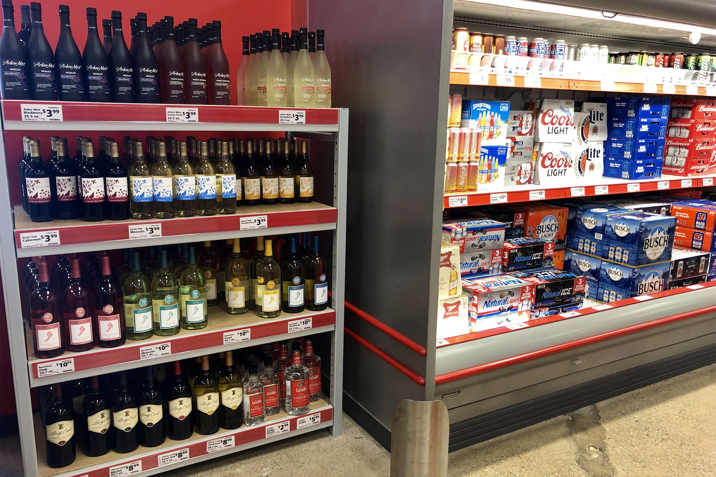 Alcohol section of Save A Lot, wine and few spirits on four shelves on left side, beer on three shelves in cooler on right side