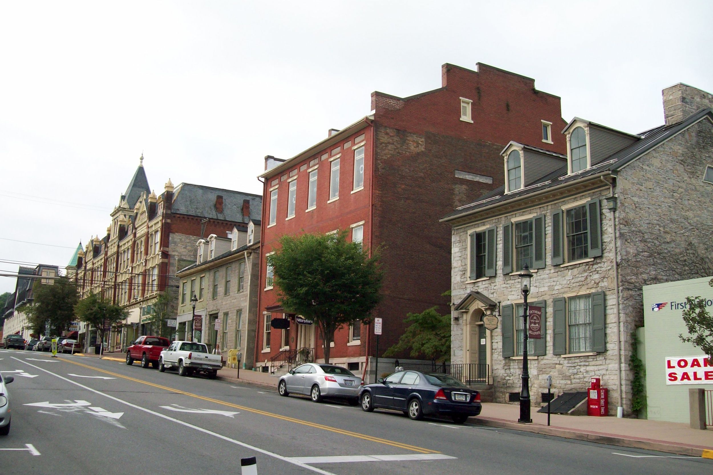 Street with business buildings made of brick in Bellefonte Historic District, Bellefonte, Pennsylvania, cars parked along the side, on a cloudy day during summer