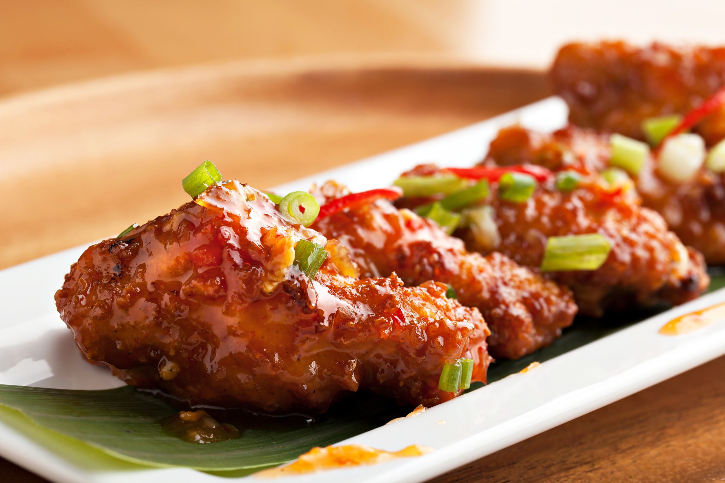 Closeup of slow cooker sweet and spicy chicken on a white porcelain rectangle plate with a blurred background