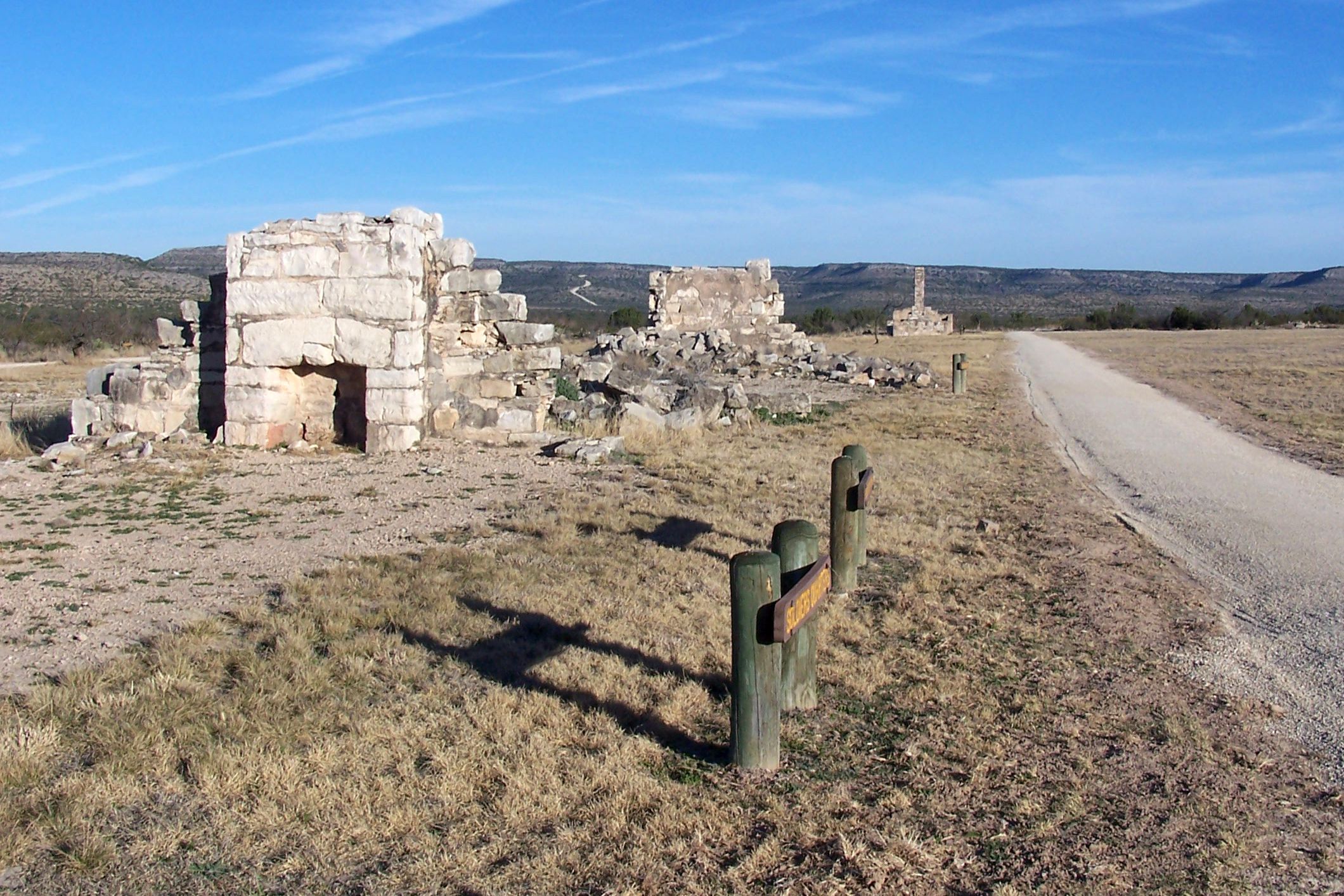 Fort Lancaster State Historic Site, Crockett County, Texas, dilapidated made out of old bricks on the left, road going off into the distance on the right, hills in the background with a blue sky on a sunny day