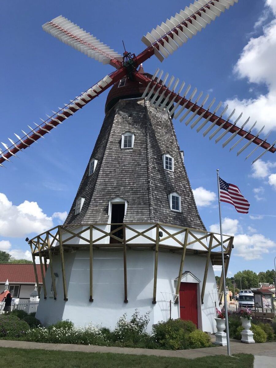Front exterior of Danish Windmill, Elk Horn, Iowa, dramatic windmill surrounded by charming flowers, a blue sky in the background on a sunny day
