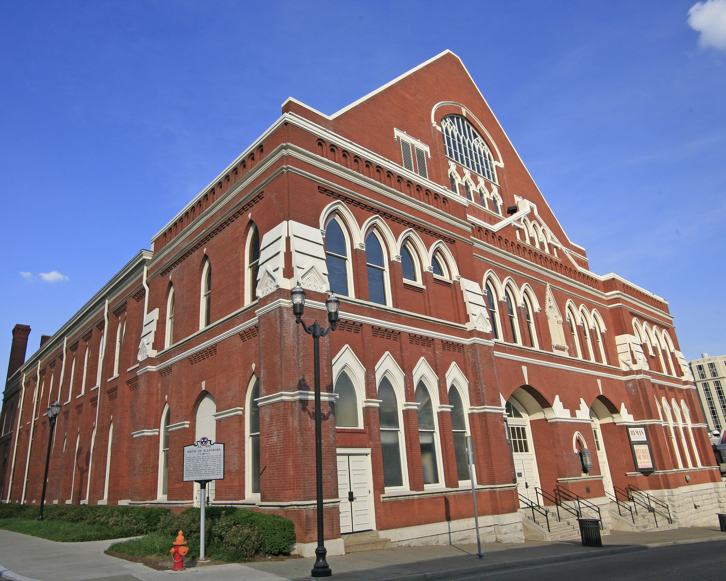 Front exterior of Ryman Auditorium, Nashville, brick building with concrete front steps, on a sunny day, a blue sky in the background