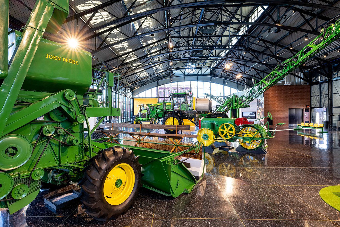 Combine and sprayer machines in interior of John Deere Pavilion, Moline, Illinois, other machines in the background, sunlight coming through windows