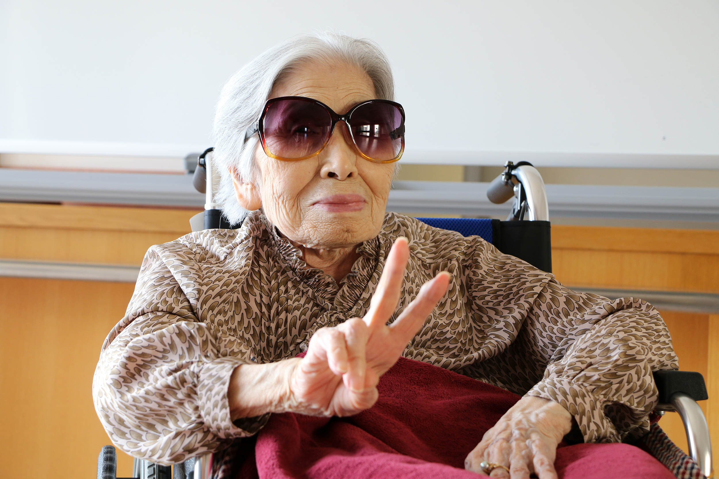 Relaxed senior woman in a wheelchair giving a peace sign