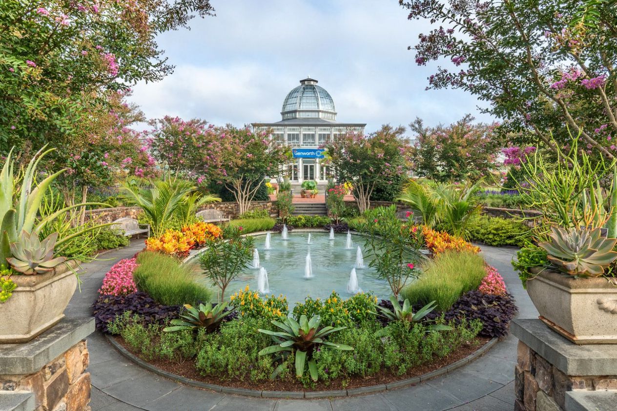 Outside garden, Lewis Ginter Botanical Garden, Richmond, Virginia, round fountain surrounded by plants and a stone walkway, colorful plants and trees, on a sunny day