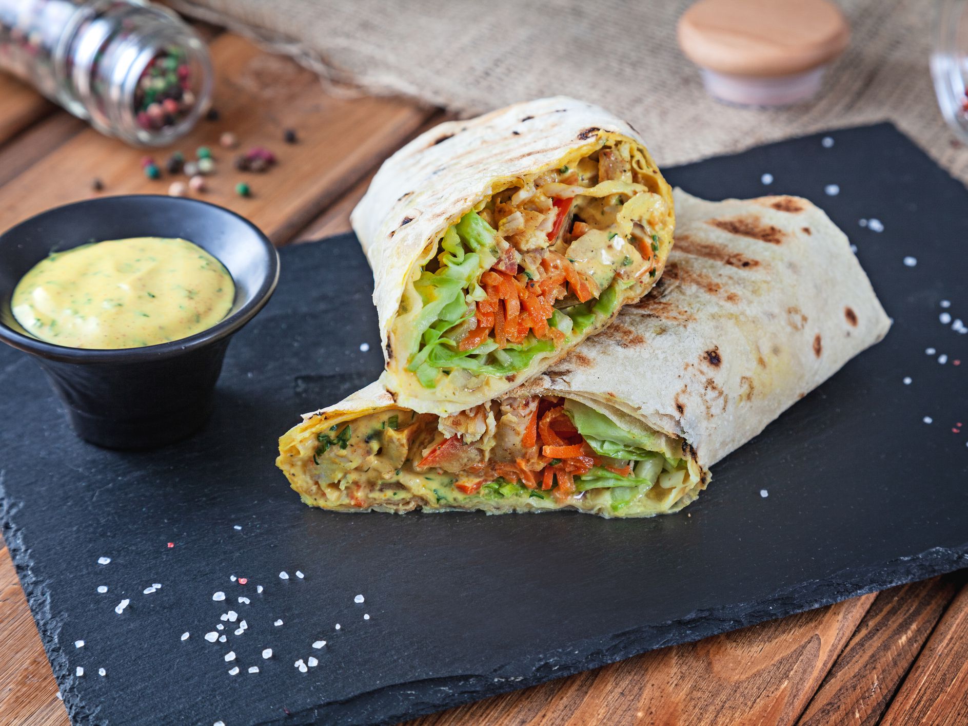 Close up view on Shawarma sandwich, gyro fresh roll in lavash. Shaurma served on black stone. Kebab in pita with copy space. Traditional Middle Eastern snack, fast food. Horizontal close up