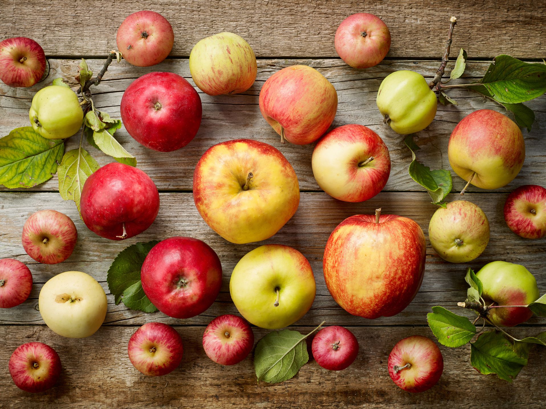 various kinds of fresh apples on wooden table, top view