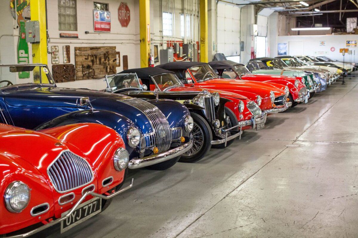 Line of shiny vintage cars inside Route 66 Car Museum, Springfield, Missouri, car and gas signs along the wall, concrete floor, bright lighting